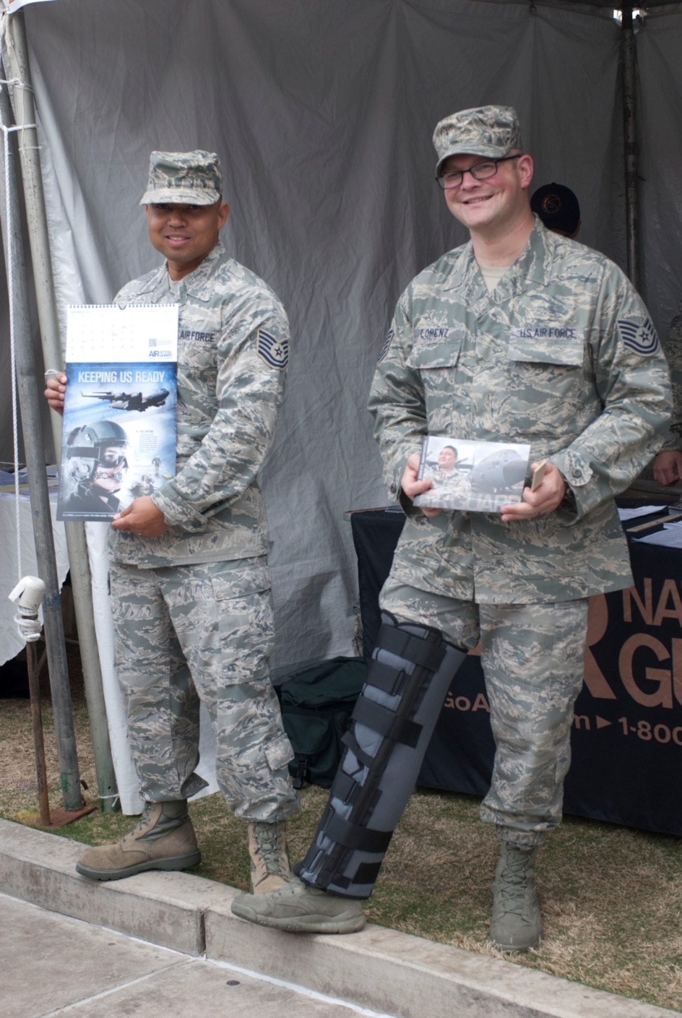 Tech. Sgts. James Wright and Andy Lorenz, recruiters at the 162nd Fighter Wing, proudly display Air National Guard paraphernalia March 9 at the Festival of Books in Tucson, Ariz. The recruiters provided the calendars and information pamphlets to festival visitors to share the wing’s presence and mission with community members. (U.S. Air Force photo by Staff Sgt. Heather Davis)