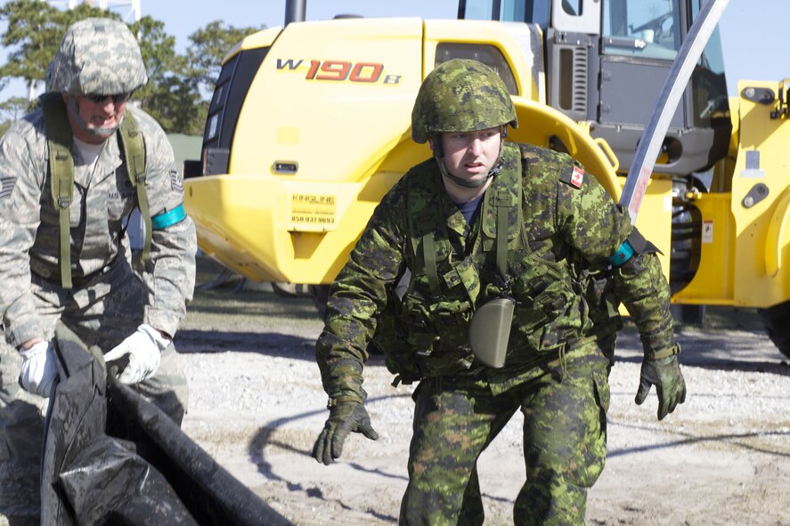 A Royal Canadian Air Force construction engineer rushes to assist in the construction of a small shelter during an exercise at the Silver Flag site March 7, 2013, at Tyndall Air Force Base, Fla. The exercise was part of a seven-day course designed to prepare U.S. Air Force civil engineers for deployment operations. Thirty one Canadians from 19th Wing, Construction Engineering Flight, Canadian Forces Base Comox, British Columbia, participated in the Silver Flag training which provided experience establishing and maintaining a base at a forward-deployed location. (U.S. Air Force photo/Eddie Green)