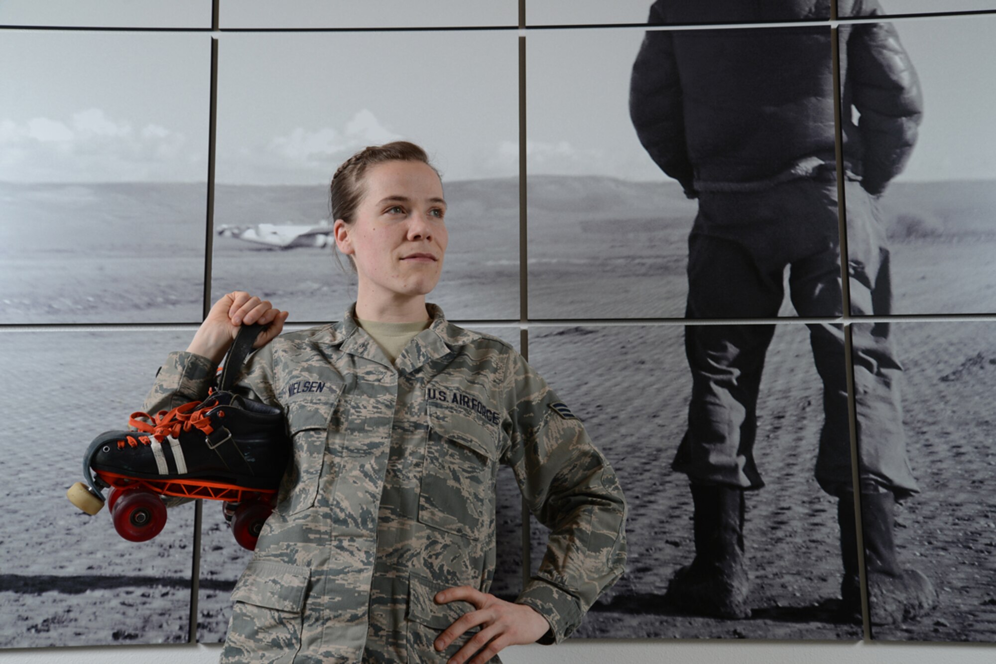 JOINT BASE ELMENDORF-RICHARDSON, Alaska -- Senior Airman Kendall Nielsen, 477th Fighter Group, poses for a portrait with her roller skates and by a Tuskegee Airmen photo mural at the fighter group's headquarters March 10. The 477th FG and the group's 302nd Fighter Squadron both have Tuskegee heritage. (U.S. Air Force photo/David Bedard)