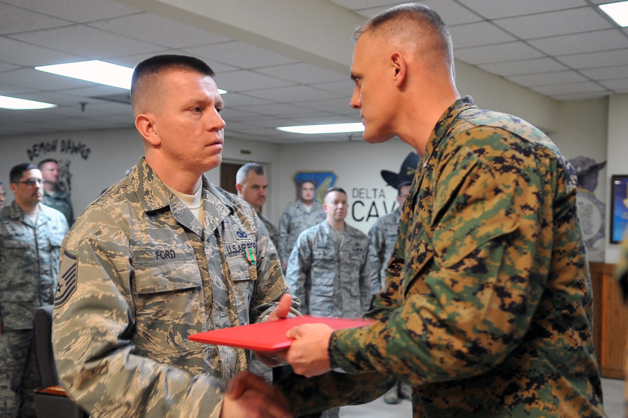 Master Sergeant Anthony Ford (left), 51st Security Forces Squadron town patrol senior NCO in charge, accepts the Navy and Marine Corps Achievement Medal from Lt. Col. Eric Drown, Marine Tactical Air Command Squadron-18, 1st Marine Air Wing commanding officer, in a ceremony at the security forces headquarters building March 13, 2013. Ford provided force protection briefs to more than 350 Marines and Sailors and courtesy patrol briefs to more than 60 Marines. Ford also personally coordinated a brief by the Osan Air Base criminal investigation division for Marines and Sailors upon arrival. (U.S. Air Force photo/Senior Airman Alexis Siekert)