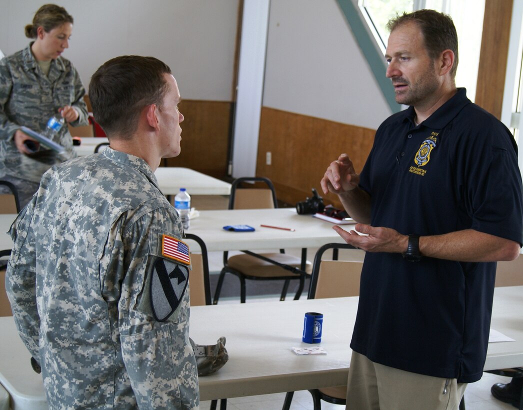 Spc. Timothy Steely, a current Operation Warfighter participant, speaks with Charles Case from the Defense Criminal Investigation Service, during a meeting held in July 2012. During the meeting, the Corps of Engineers spoke to other agencies about the program and how they can become involved. 