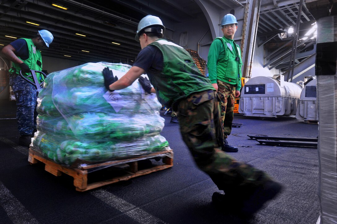 U.S. sailors move pallets of cargo aboard the aircraft carrier USS John C. Stennis in the U.S. 5th Fleet area of responsibility, March 9, 2013.
