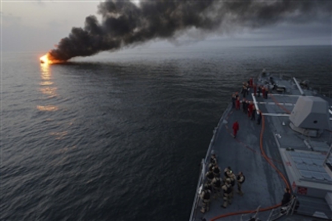 Sailors aboard the guided-missile destroyer USS William P. Lawrence (DDG 110) prepare to offer rescue assistance to a burning vessel during a transit of the Strait of Hormuz on March 11, 2013.  The Lawrence is deployed in support of maritime security operations and theater security cooperation efforts in the U.S. 5th Fleet area of responsibility.  