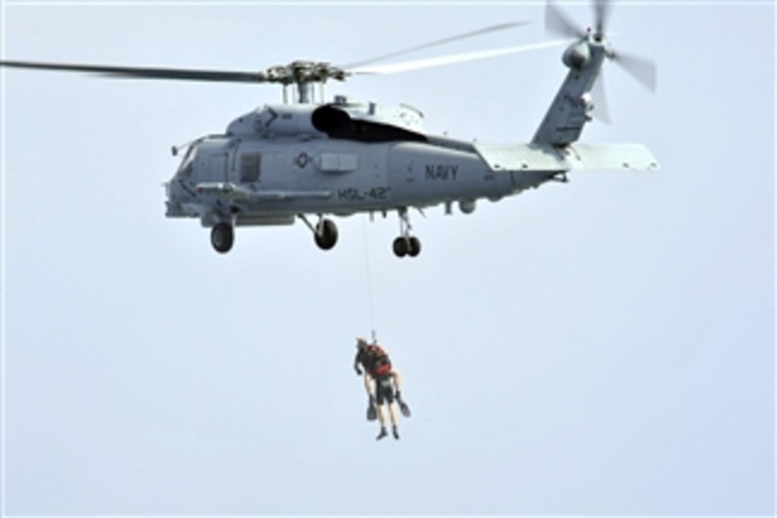 U.S. Navy rescue swimmers are hoisted from the water by an SH-60B Sea Hawk helicopter during a search and rescue exercise at sea on March 11, 2013.  The Sea Hawk is attached to Helicopter Anti-submarine Squadron Light 42 and is deployed aboard the guided-missile destroyer USS Jason Dunham (DDG 109).  The Dunham is deployed in support of maritime security operations and theater security cooperation efforts in the U.S. 5th Fleet area of responsibility.  