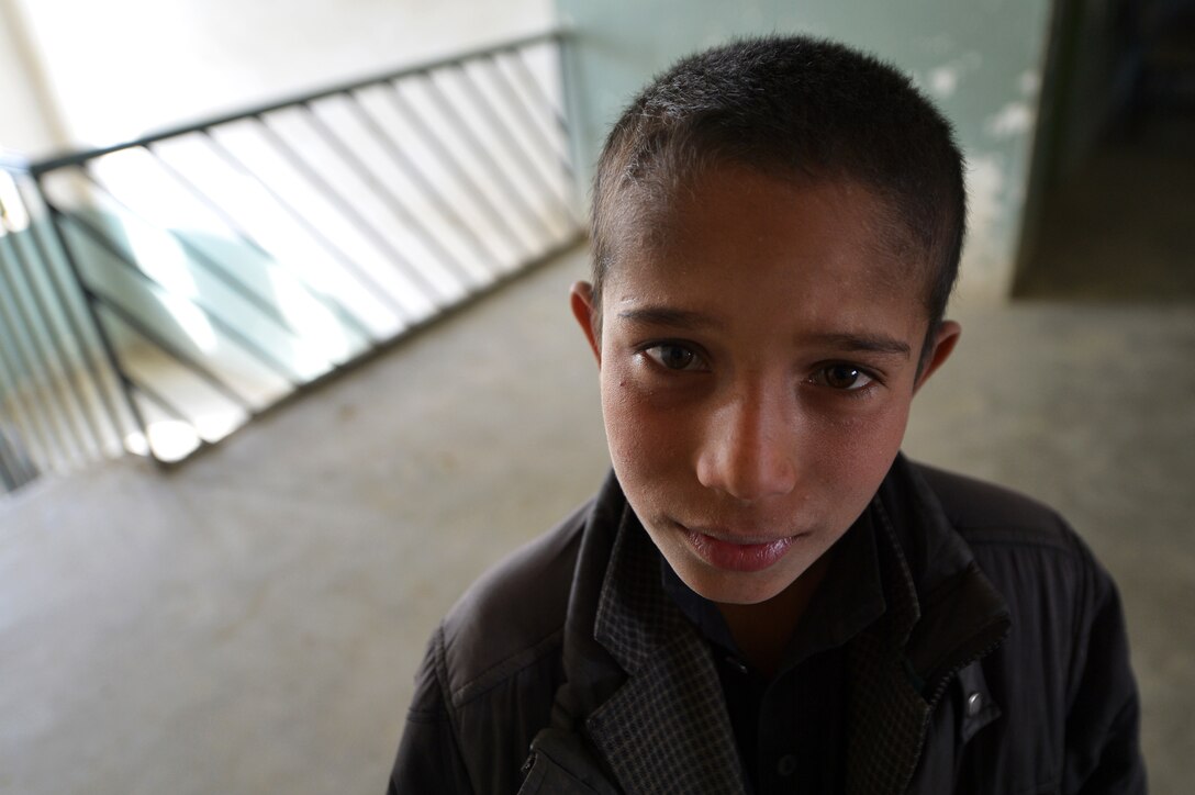 A local Afghan boy watches as members of the 755th Expeditionary Security Forces Squadron Reaper Team 1 patrol a school near Bagram Airfield, Afghanistan, March 11, 2013. The 755th ESFS Reaper teams operate missions “outside the wire” providing security during key leader engagements and meetings with the local community. (U.S. Air Force photo/Senior Airman Chris Willis)