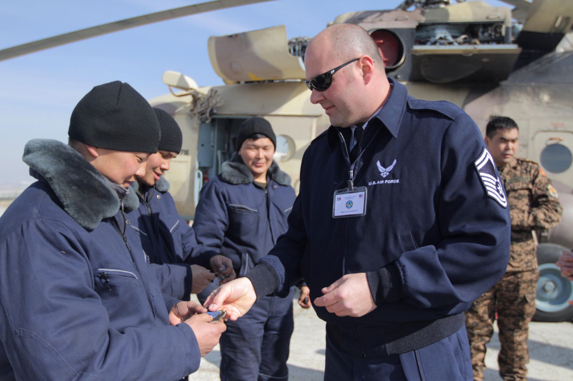 Senior Master Sgt. Kenneth Joyce gives Alaska Air National Guard unit patches to Mongolian Air and Air Defense Force aircraft maintenance personnel while touring facilities and viewing aircraft at Chinggis Khaan Air Base, Mongolia. Joyce and three other Alaska Air National Guardsmen were in Ulaanbaatar last week for an aviation maintenance exchange to educate Mongolian Air and Air Defense Force members on the C-130 Hercules. (Alaska National Guard photo/Air National Guard Maj. Guy Hayes)