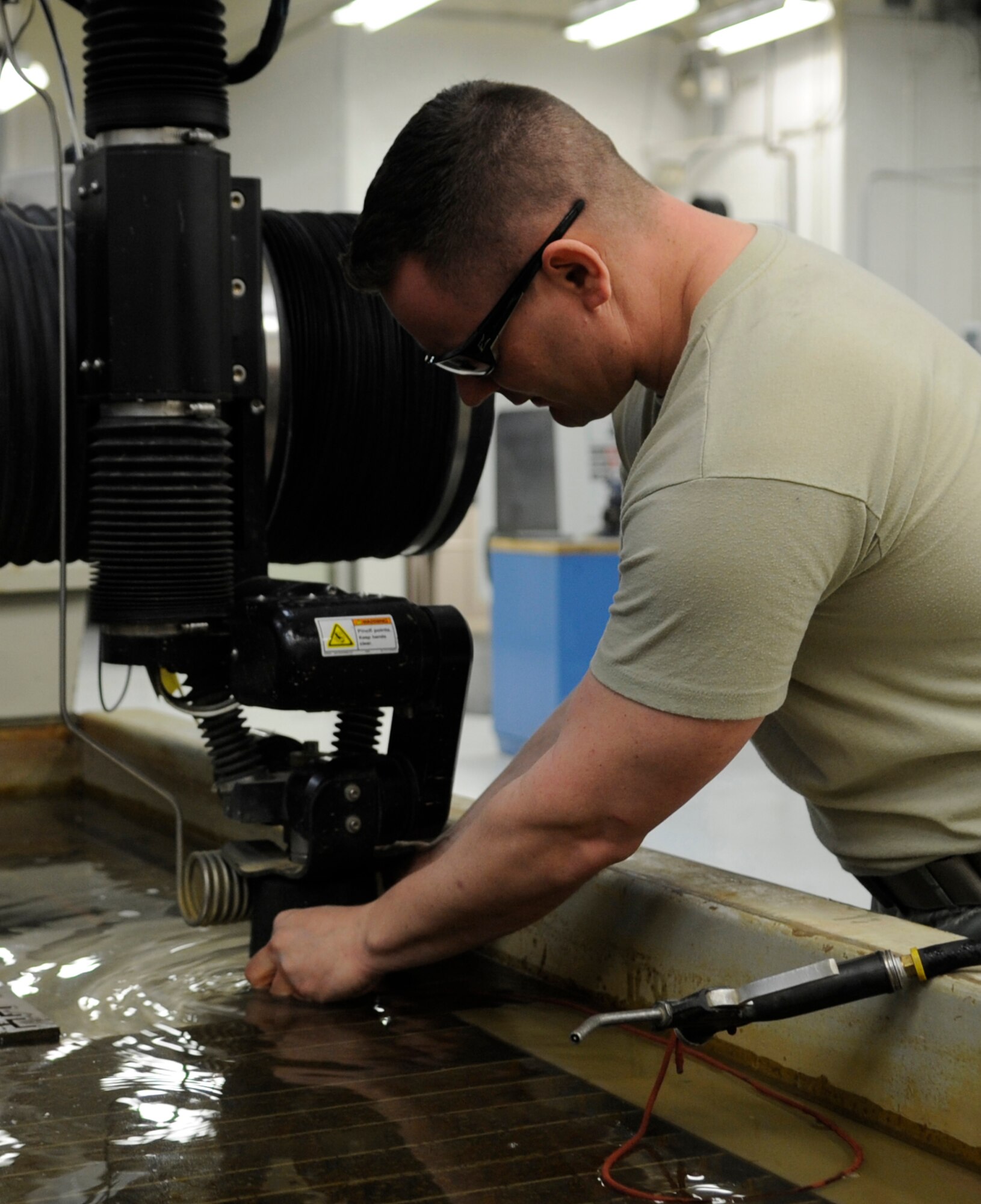 WHITEMAN AIR FORCE BASE, Mo. – U.S. Air Force Tech. Sgt. Jim Gargano, 509th Maintenance Squadron metals technology assistant section chief, uses a water jet machine to cut pieces of metal for aircraft parts, Mar. 6. Water jets do not leave heat-affected zones, generate noxious fumes or create mechanical stresses on the surfaces of the cut piece. (U.S. Air Force photo/Staff Sgt. Alexandra M. Boutte) (RELEASED)