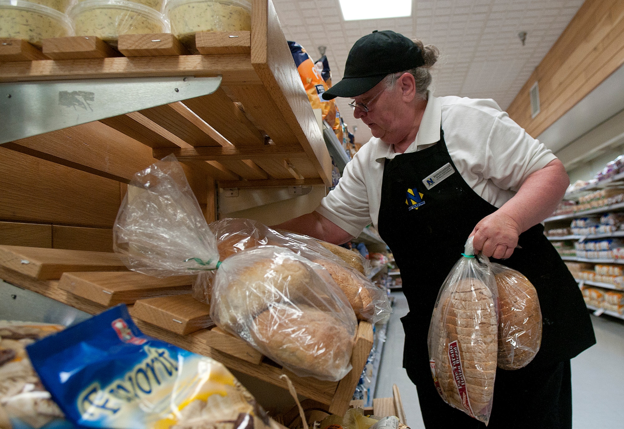 Barbara Damoude arranges freshly baked bread products on the F. E. Warren Air Force Base Commissary shelves prior to its opening March 10. (U.S. Air Force photo by R.J. Oriez)
