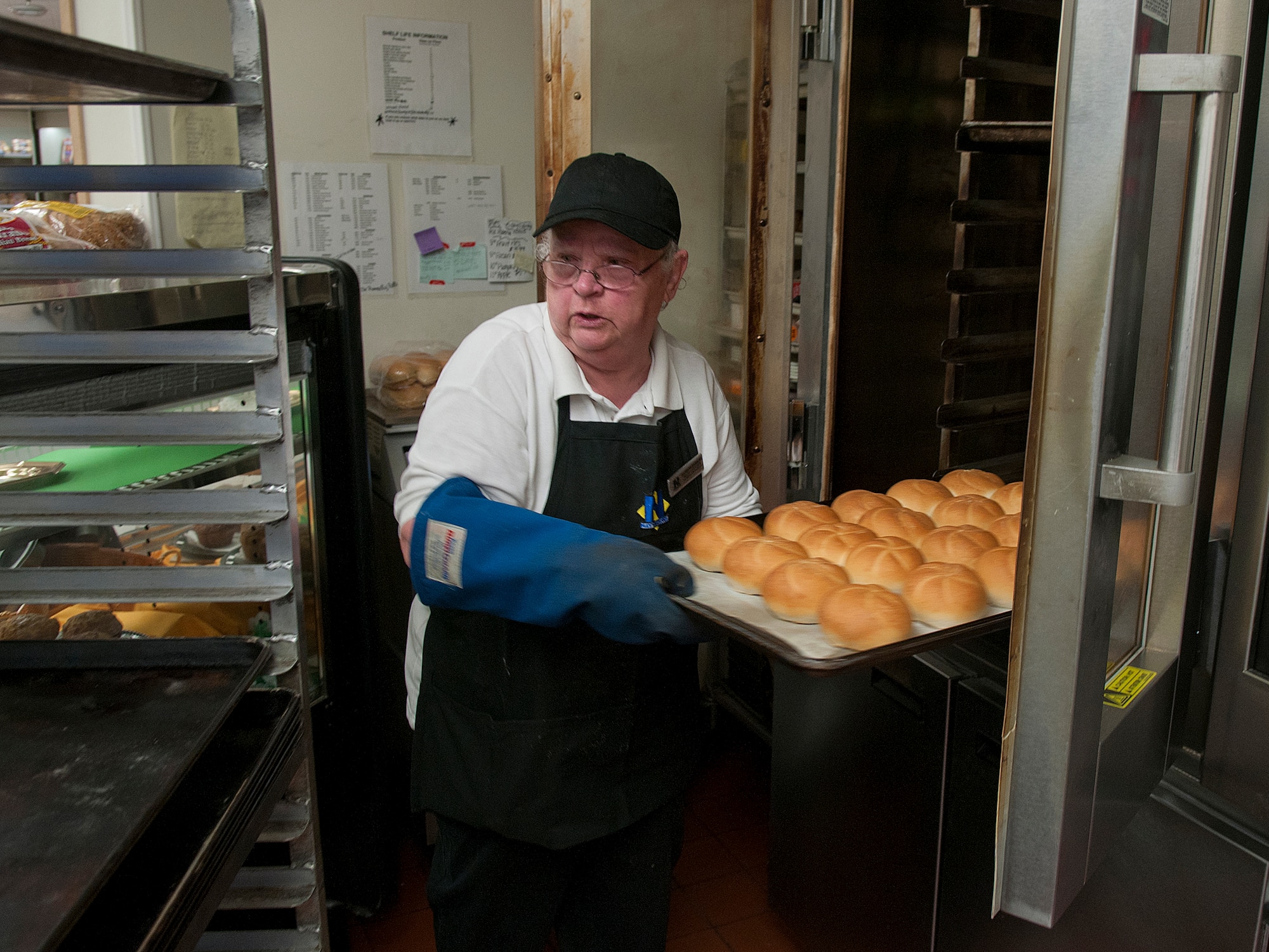 Barbara Damoude pulls freshly-baked Kaiser Rolls from the oven in the F. E. Warren Air Force Base Commissary Bakery March 10. (U.S. Air Force photo by R.J. Oriez)