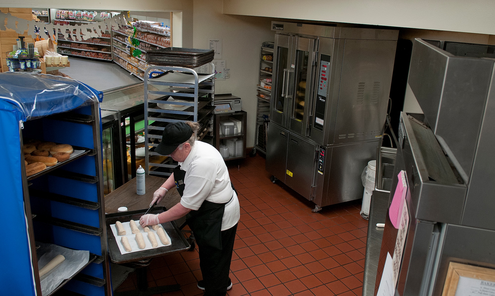 Barbara Damoude scores the top of whole-wheat dough before placing it in the proofer in the tight space of the F. E. Warren Air Force Base Commissary Bakery March 10. Damoude has been a baker with the commissary for 11 years. (U.S. Air Force photo by R.J. Oriez)