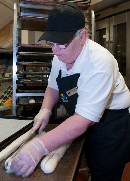 Barbara Damoude slits the top of dough destined to become Italian bread before placing it in the proofer in the F. E. Warren Air Force Base Commissary Bakery March 10. Damoude comes in two hours before the commissary opens to prepare the day’s bakery goods. (U.S. Air Force photo by R.J. Oriez)