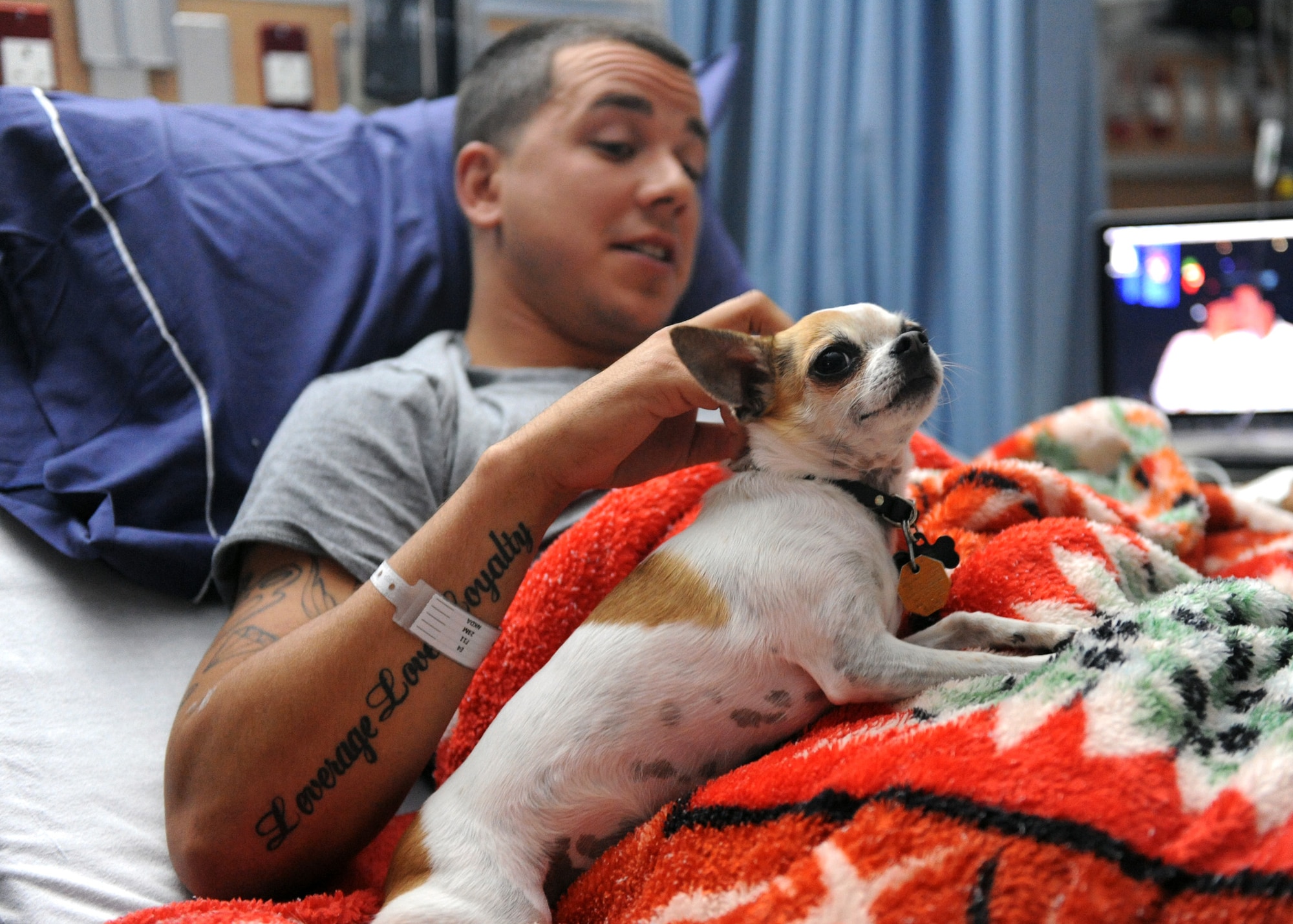 SOUTHWEST ASIA – Senior Airman Carlos Cassano, 379th Expeditionary Logistics Readiness Squadron, receives a visit from Balad March 13 at the 379th Expeditionary Medical Group Clinc. Cassano said Balad was a nice treat to break up some time. As a trained therapy dog, Balad is able to visit patients at the 379th Expeditionary Medical Group Clinic and gives the379th EMDG the distinction of having the first therapy dog program in the U.S. Central Command area of responsibility. (U.S. Air Force photo/Senior Airman Joel Mease)