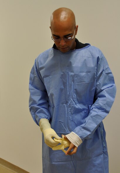 Joseph Vargo puts on gloves at the Charles C. Carson Center for Mortuary Affairs, Dover Air Force Base, Del. Vargo is one of three civilian embalming technicians with Air Force Mortuary Affairs Operations. The gloves are just one part of the personal protective equipment technicians wear while performing their duties of assisting licensed embalmers who preserve the remains of fallen service members. (U.S. Air Force photo/Christin Michaud)