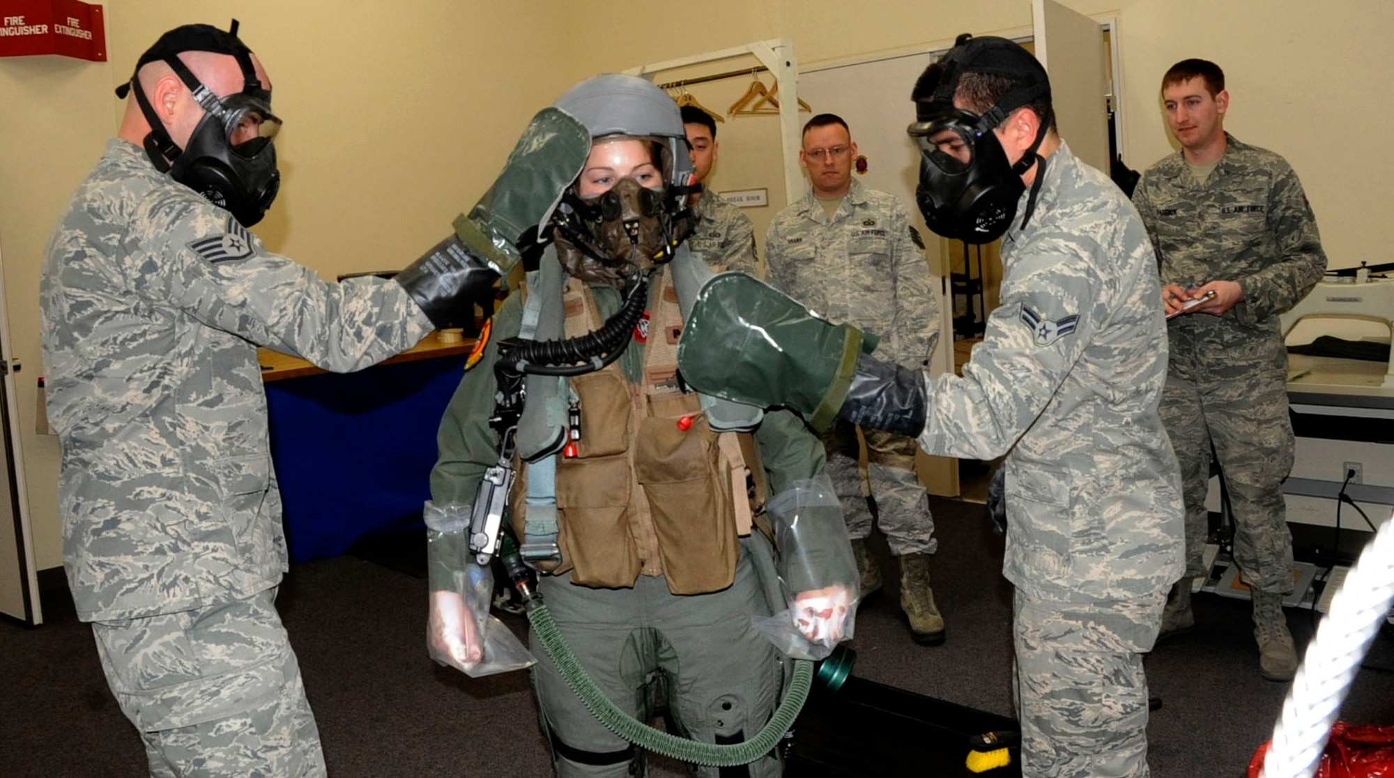 U.S. Air Force Staff Sgt. Bryan Reuse, 14th Fighter Squadron NCOIC of aircrew flight equipment, left, and Airman 1st Class Robert McClung, 35th Operations Support Squadron aircrew flight equipment technician, left, wipes down Capt. Jessa Charron, 13th Fighter Squadron, center, during a chemical, biological, radiological, and nuclear defense exercise at Misawa Air Base, Japan, March 15, 2013. The aircrew flight equipment flight’s responsibility is to maximize each pilot’s performance by making sure all products are up-to-date and safe enough to protect and sustain human life during flight operations. (U.S. Air Force photo by Airman 1st Class Kenna Jackson)