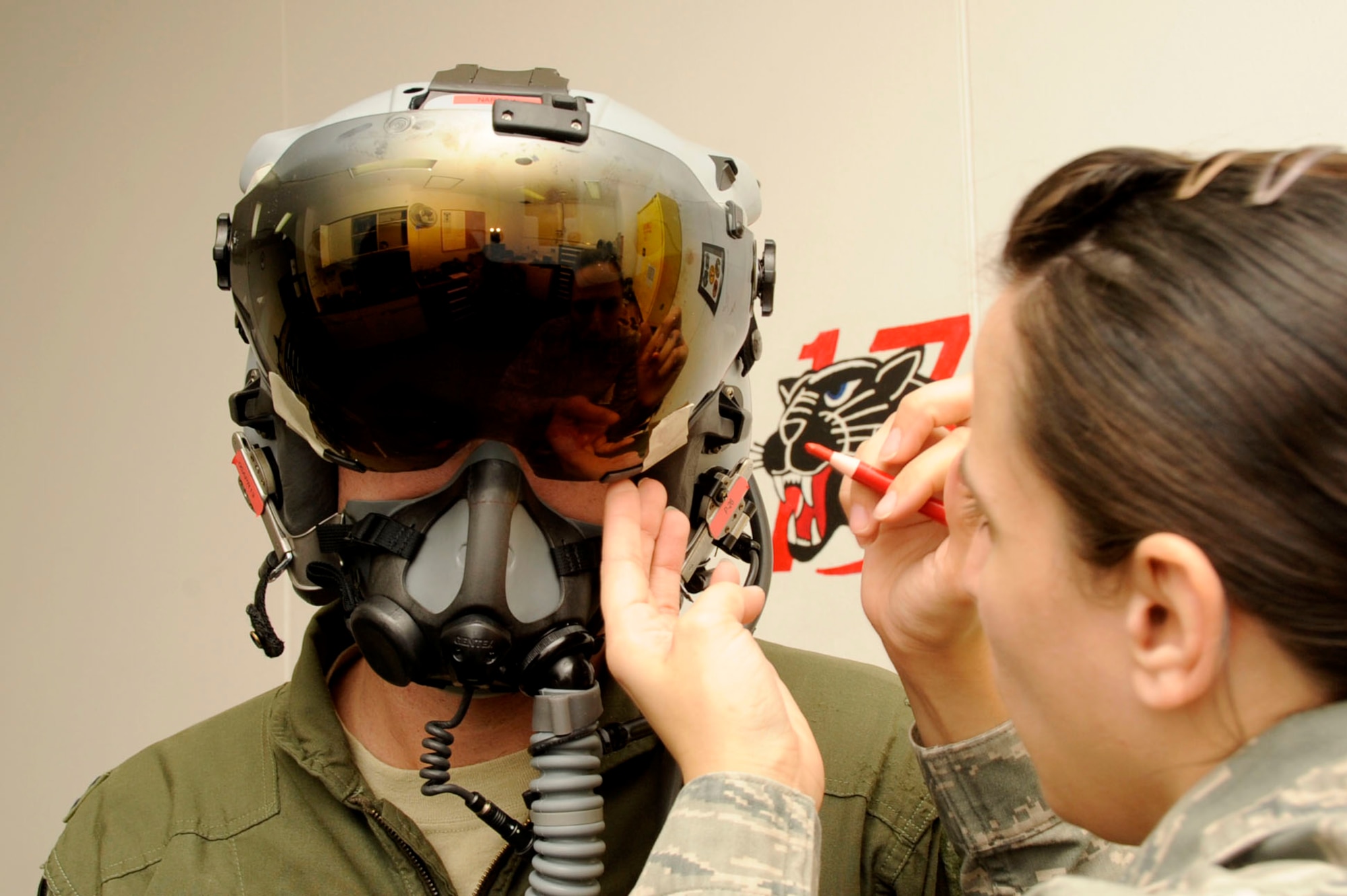 U.S. Air Force Senior Airman Courtney Maleport, 35th Operations Support Squadron aircrew flight equipment technician, makes adjustments to Capt. Christopher Nations’, 13th Fighter Squadron pilot, helmet at Misawa Air Base, Japan, March 14, 2013. AFE airmen are responsible for function checking helmets, parachutes, floatation devices, and other emergency protective equipment. Not only do they test every piece of equipment pilots use during flight or in an emergency scenario, they maintain and inspect them regularly. (U.S. Air Force photo by Airman 1st Class Kenna Jackson)