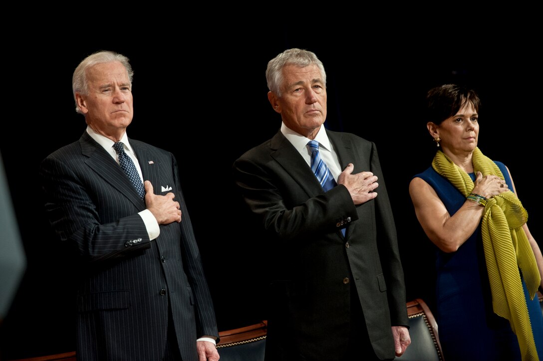 Vice President Joe Biden, left, Defense Secretary Chuck Hagel and his wife, Lilibet, honor the playing of the national anthem during a swearing-in and welcome ceremony for Hagel at the Pentagon, March 14, 2013.