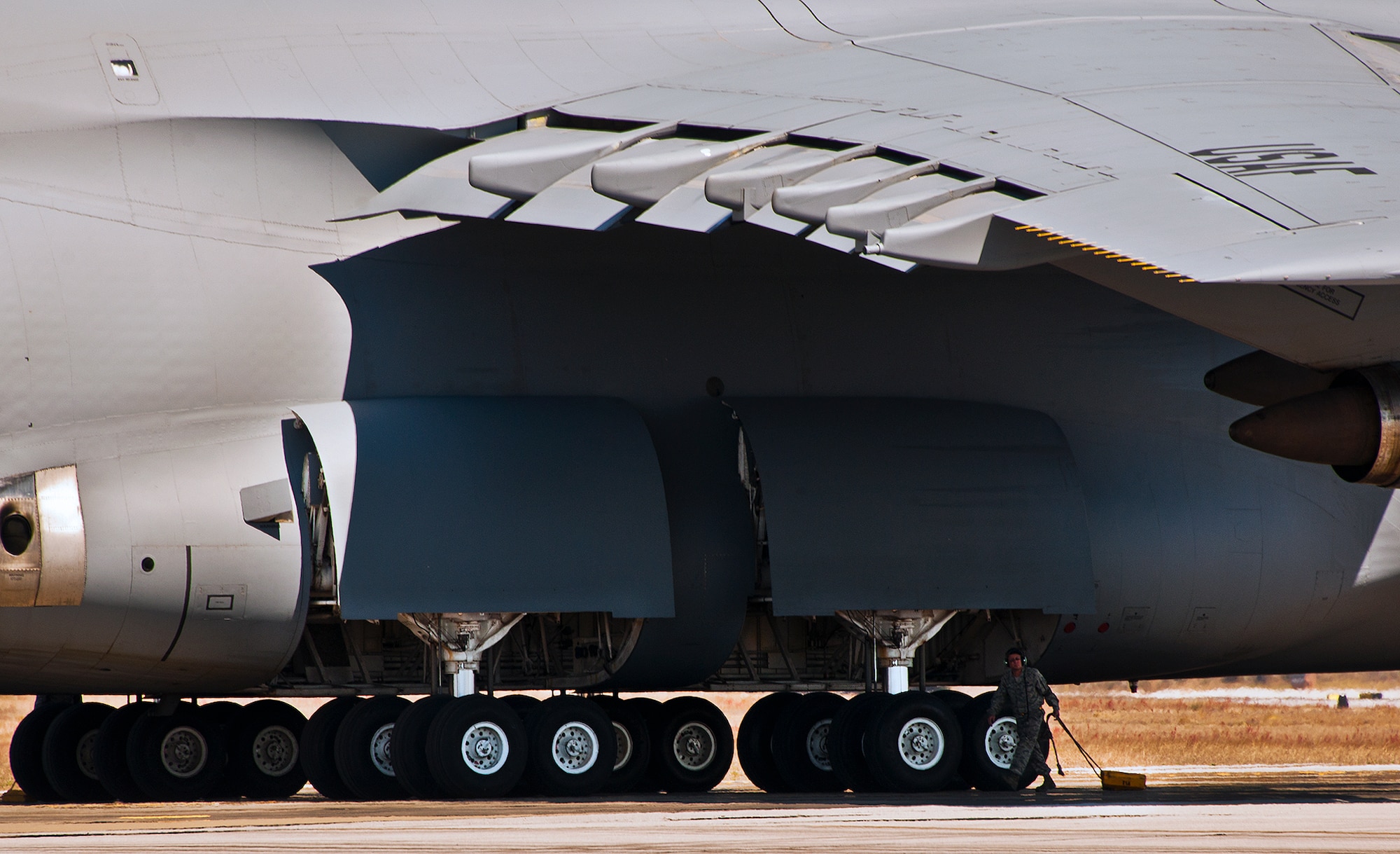 A 433rd Airlift Wing maintainer carries chocks to secure the wheels of a C-5 Galaxy just after its arrival at Eglin Air Force Base, Fla., March 14.  The reserve wing’s aircraft brought maintenance equipment from the 482nd Fighter Wing to the base in preparation for the weapons system evaluation program taking place March 18-22.  (U.S. Air Force photo/Samuel King Jr.)