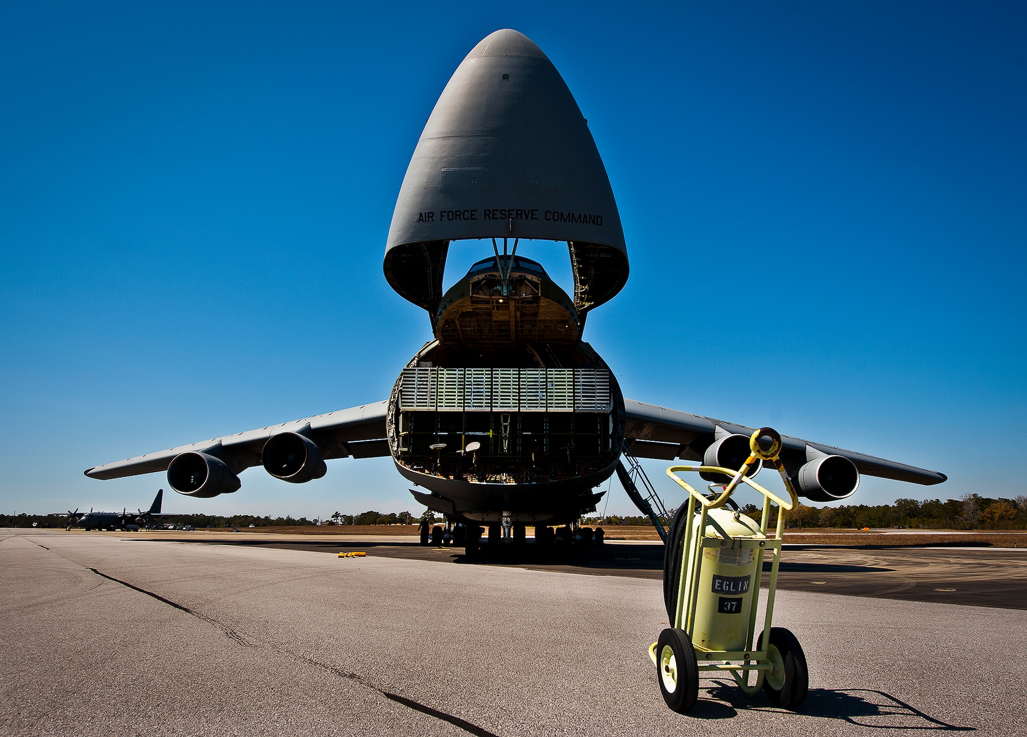 The nose of a C-5 Galaxy, from the 433rd Airlift Wing, lifts up so aircrew and 96th Test Wing air transportation Airmen can begin off-loading equipment at Eglin Air Force Base, Fla., March 14.  The reserve wing’s aircraft brought maintenance equipment from the 482nd Fighter Wing to the base in preparation for the weapons system evaluation program taking place March 18-22.  (U.S. Air Force photo/Samuel King Jr.)