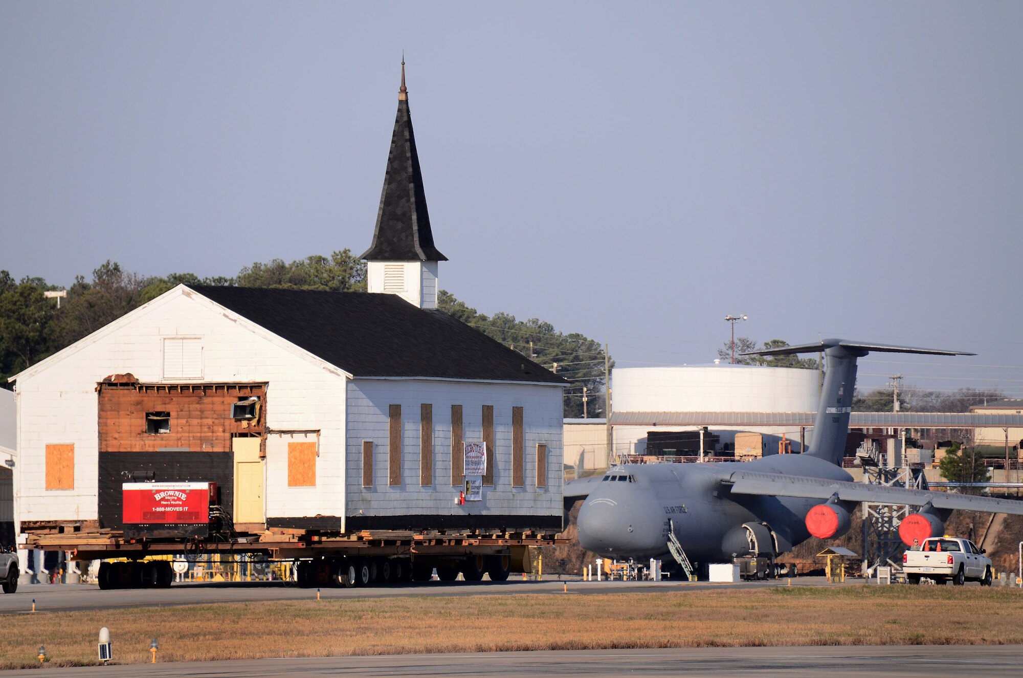 The Dobbins chapel is towed past Lockheed Martin facilities and a C-5 Galaxy, on its way to the Clay Army National Guard camp on the south side of the Dobbins runway, Dobbins ARB, Ga., March. 17. The 30 ton load is supported by several heavy steel beams, wood cribbing, and three hydrostatic dolly assemblies which are all towed by a heavy-duty front-end loader.  To meet post-9/11 security requirements, new construction of a perimeter road and parking lot at the chapel site dictated the chapel must be removed.  The private, non-profit Dobbins Chapel Foundation, 94th Airlift Wing and Georgia National Guard arrived at a solution at no cost to the government, to move the historic chapel across the base. (U.S. Air Force photo/Brad Fallin)