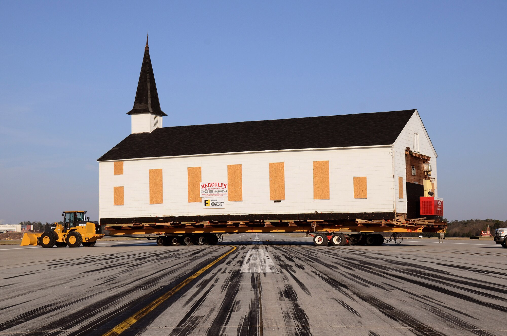 The Dobbins chapel is towed across the main runway, on its way to the Clay Army National Guard camp on the south side of the Dobbins runway, Dobbins ARB, Ga., March. 17. The 30 ton load is supported by several heavy steel beams, wood cribbing, and three hydrostatic dolly assemblies which are all towed by a heavy-duty front-end loader.  The 30 ton load is supported by several heavy steel beams, wood cribbing, and three hydrostatic dolly assemblies which are all towed by a heavy-duty front-end loader.  To meet post-9/11 security requirements, new construction of a perimeter road and parking lot at the chapel site dictated the chapel must be removed.  The private, non-profit Dobbins Chapel Foundation, 94th Airlift Wing and Georgia National Guard arrived at a solution at no cost to the government, to move the historic chapel across the base. (U.S. Air Force photo/Brad Fallin)