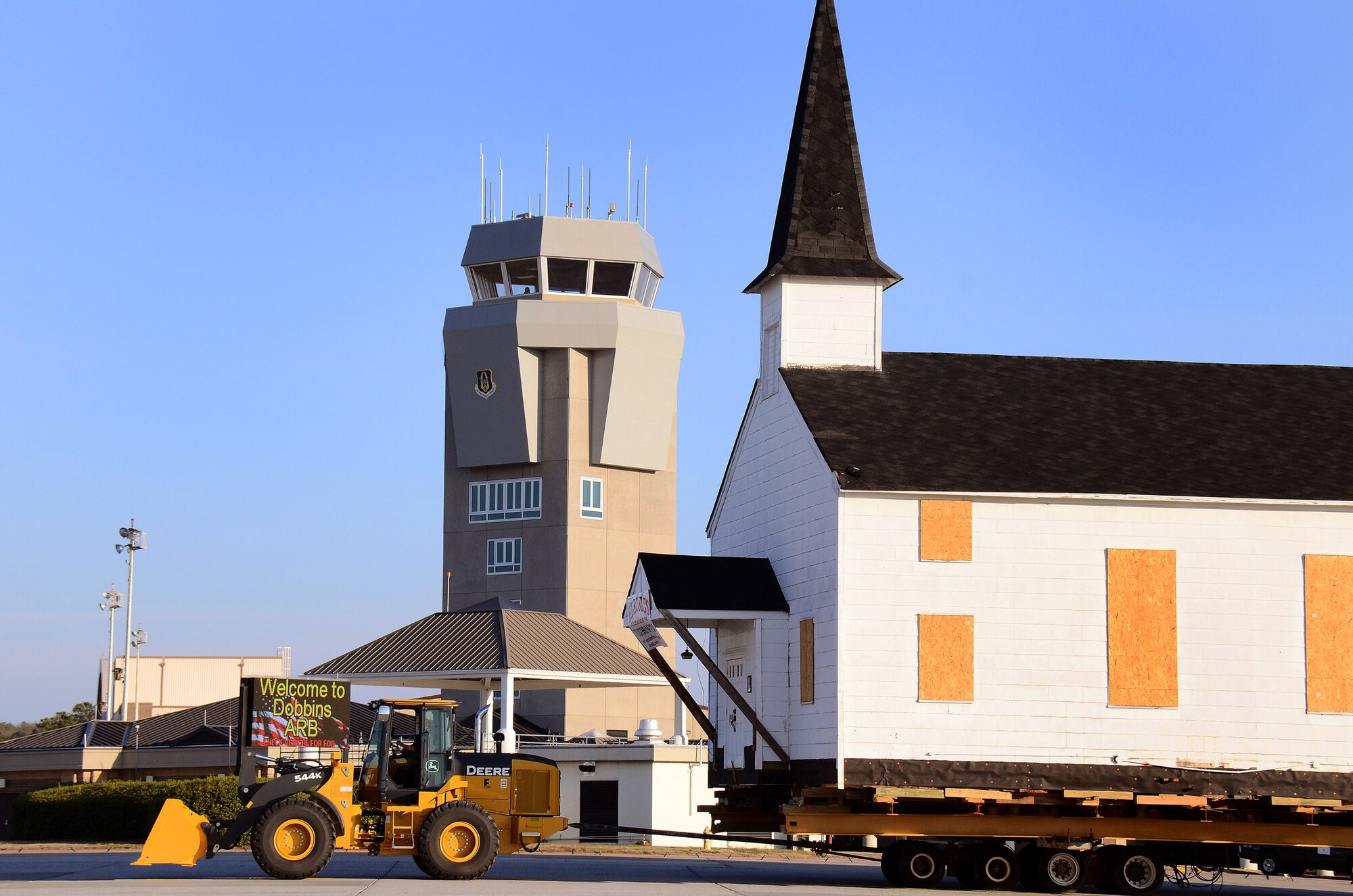 The Dobbins chapel is towed down the flight line, past the control tower, on its way to the Clay Army National Guard Camp on the south side of the Dobbins Air Reserve Base runway,  Ga., March. 17. The over 130 ton load is supported by several heavy steel beams, wood cribbing, and three hydrostatic dolly assemblies which are all towed by a heavy-duty front-end loader.  To meet post-9/11 security requirements, new construction of a perimeter road and parking lot at the chapel site dictated the chapel must be removed.  The private, non-profit Dobbins Chapel Foundation, 94th Airlift Wing and Georgia National Guard arrived at a solution at no cost to the government, to move the historic chapel across the base. (U.S. Air Force photo/Brad Fallin)