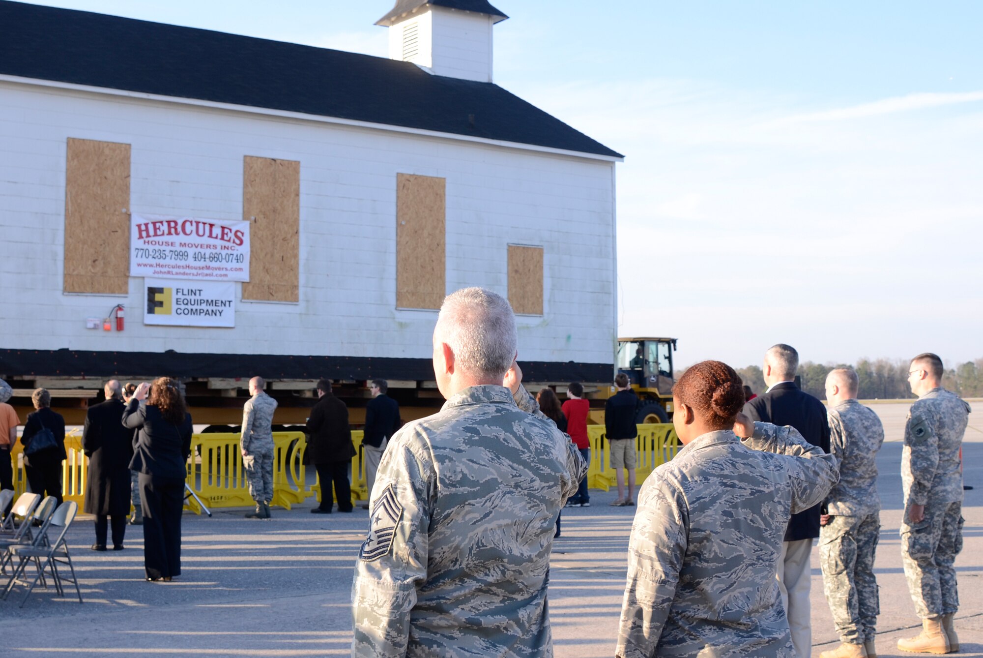 Reservists and other personnel render salutes as the Dobbins Air Reserve Base chapel begins a two- mile relocation move across the base runway to Camp Clay Army National Guard Camp following a ceremony commemorating the event here March 17. Dobbins has been home to the chapel for over 60 years and has played a large role in member’s lives both past and present. (U.S. Air Force photo/Don Peek)