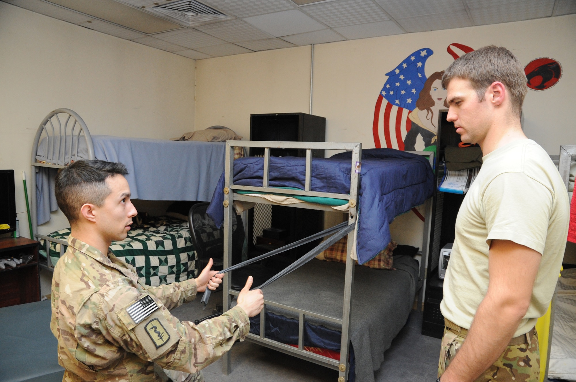 Capt. (Dr.) Kent Do, 455th Expeditionary Medical Operations Squadron physical therapist, demonstrates a muscle stretching exercise to 1st Lt. Matthew Pfarr, 83rd Expeditionary Rescue Squadron pilot, at the 83rd ERQS building on Bagram Airfield, Afghanistan, March 14, 2013. Do regularly visits units to offer diagnoses and treatment to members who cannot get to the Craig Joint Theater Hospital. (U.S. Air Force photo/Staff Sgt. David Dobrydney)