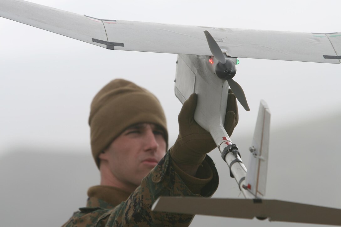 Inspecting the RQ-11B, Lance Cpl. Thomas G. Dilzer, an intelligence specialist for 1st Marine Division, prepares the unmanned aerial vehicle for a training flight in windy conditions at Camp Pendleton, Calif., February 11, 2011. The RQ-11B, or Raven B, is the only UAV currently also used by the Marines of 25th Marine Regiment. A group of unmanned aerial vehicle operators and support personnel from Headquarters Company, 25th Marine Regiment and 1st Battalion, 25th Marine Regiment ventured out into a snowy morning March 9 to conduct practice flights at Devens Reserve Forces Training Area. The flights mark the first time UAVs have been employed by the regiment.