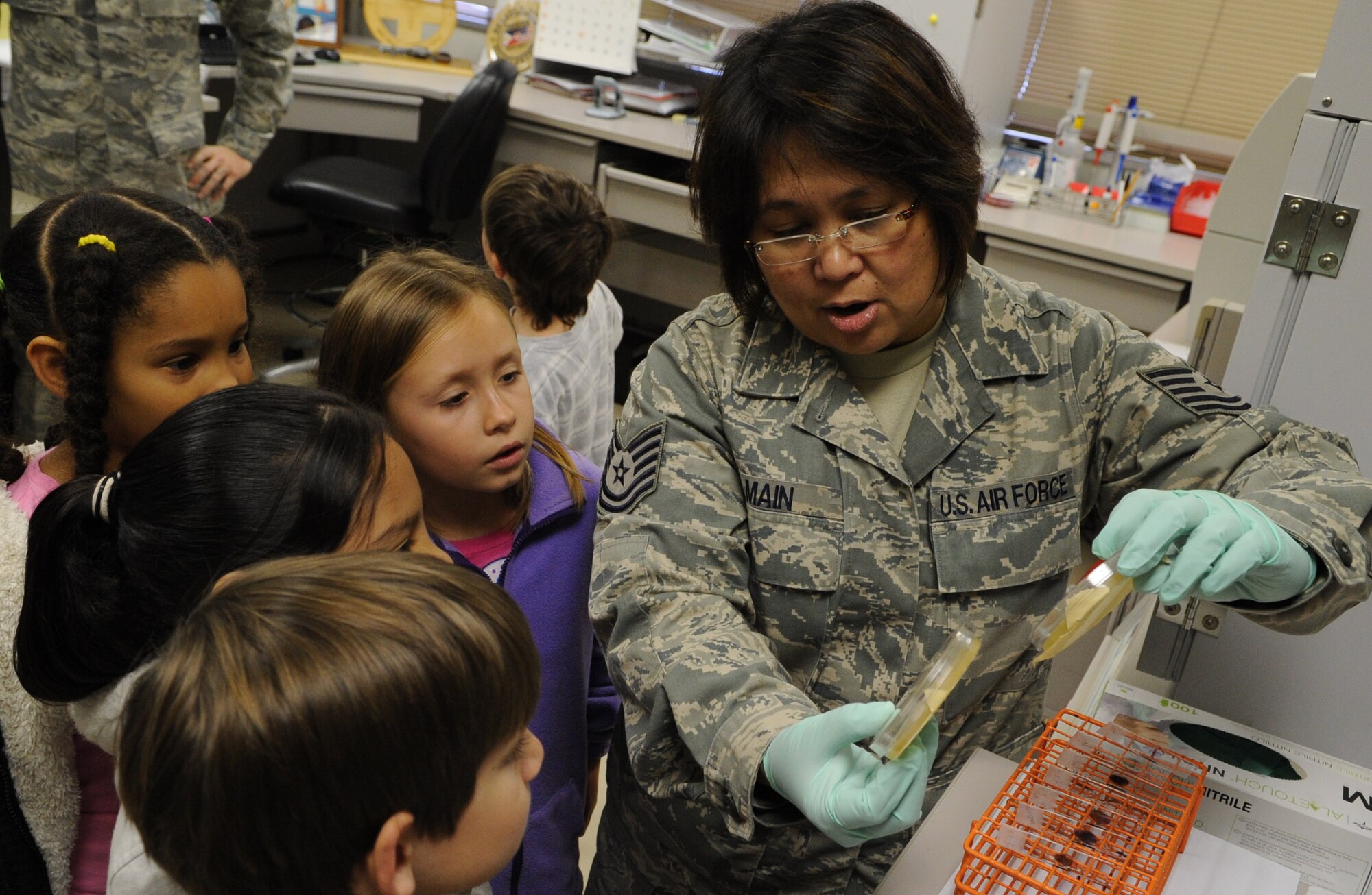 U.S. Air Force Tech. Sgt. Rowena Main, 18th Medical Support Squadron NCO in charge of microbiology, shows elementary students bacteria samples on Kadena Air Base, Japan, March 14, 2013. The students conducted a science project where they grew bacteria cultures in their classroom, with the assistance of the medical laboratory. (U.S. Air Force photo/Airman 1st Class Keith A. James)