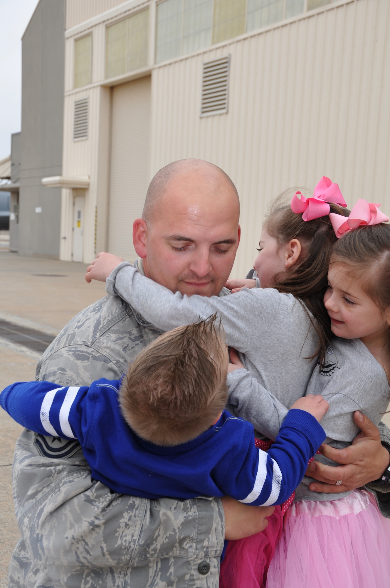 Tech. Sgt. Shaun Erickson receives an overwhelming greeting by his children.  Twin daughters Gabby and Lilly and son Parker greet their father with teary eyes after their first-ever separation.  Erickson returns home after more than two months in Southwest Asia.  (U.S. Air Force photo by Senior Airman Mark Hybers)