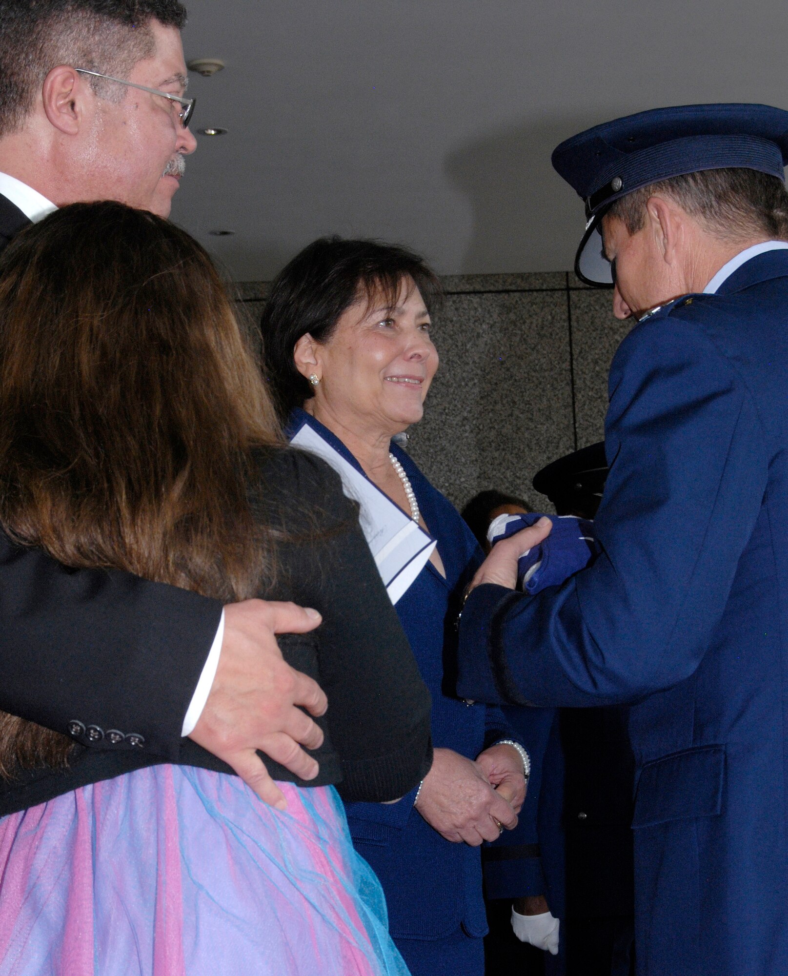 Tina Bush (center) receives a flag from Air Force Academy Superintendent Lt. Gen. Mike Gould during a memorial service March 16, 2013, for Chuck Bush, the first African American to graduate from the Academy. The couple was married for 48 years. Chuck Bush, who graduated from the Academy in 1963, died Nov. 5, 2012, at his home in Lolo, Mont. Also pictured are Michael Wills (left) and Grace Wills (lower left). (U.S. Air Force photo/Don Branum)