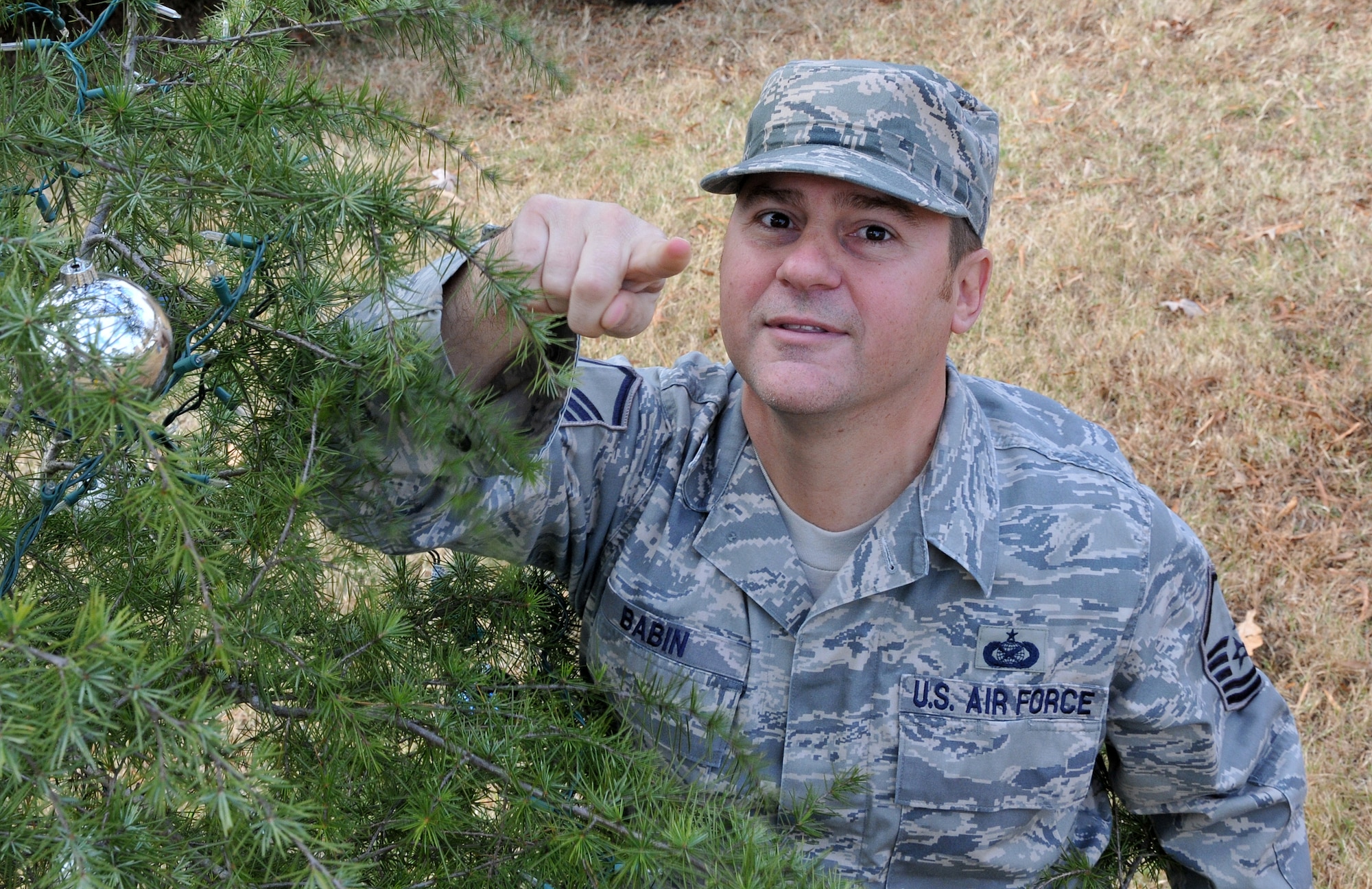Master Sgt. Chance Babin, 94th Airlift Wing public affairs specialist, multitasks between decorating the holiday tree and mentoring young photojournalists. Members of the First Four, on behalf of Chief Master Sgt. Wendell Peacock, 94th Airlift Wing command chief, invited Dobbins Air Reserve Base personnel out to decorate the base holiday tree near the front gate, Nov. 30.(U.S. Air Force photo/Senior Airman Elizabeth Van Patten)