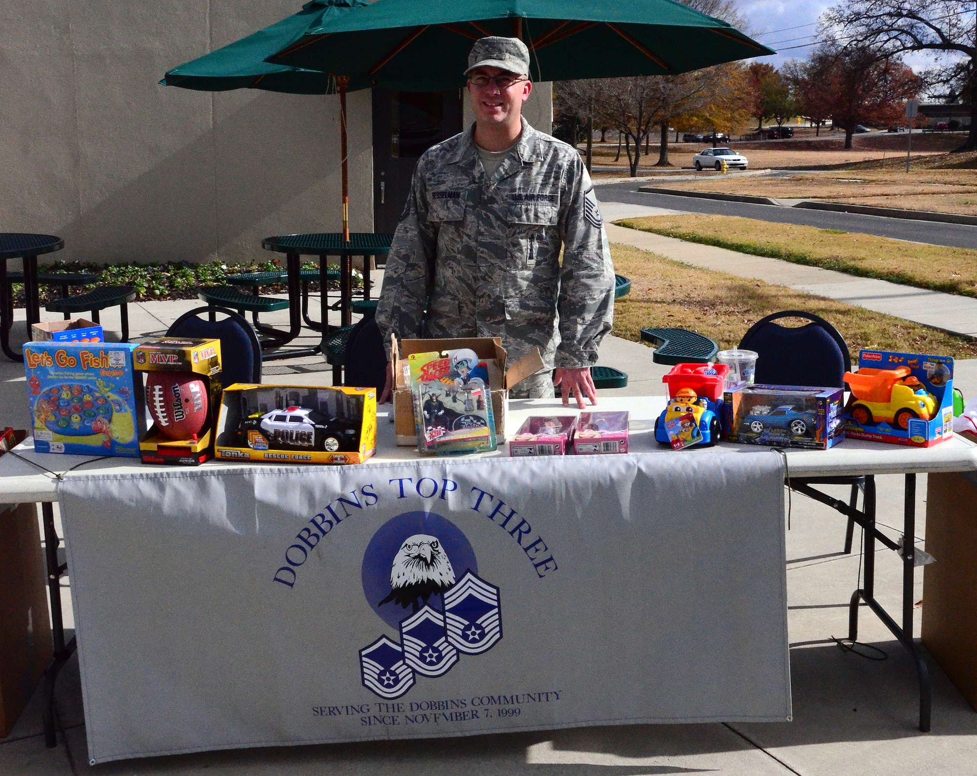 Master Sgt. John Besselman, of the 94th Civil Engineering Squadron, mans the "Coins for Toys" table at the Dobbins Consolidated Club during the December unit training assembly. The Top Three collected $1400 in the form of toys this holiday season. (U.S. Air Force photo/Senior Airman Elizabeth Van Patten)