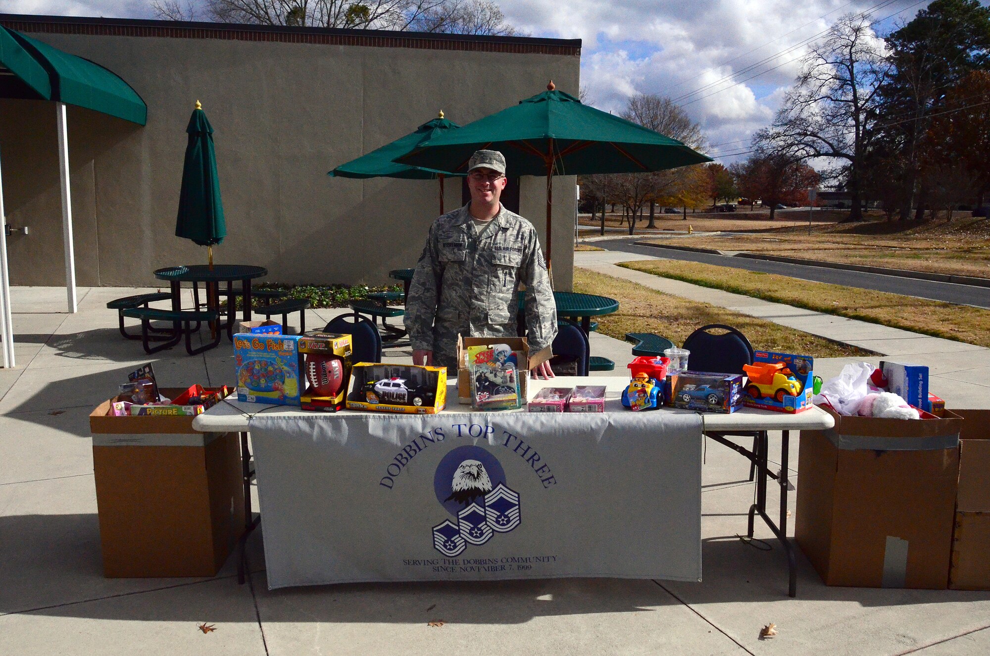 Master Sgt. John Besselman, of the 94th Civil Engineering Squadron, mans the "Coins for Toys" table at the Dobbins Consolidated Club during the December unit training assembly. The Top Three collected $1400 in the form of toys this holiday season. (U.S. Air Force photo/Senior Airman Elizabeth Van Patten)