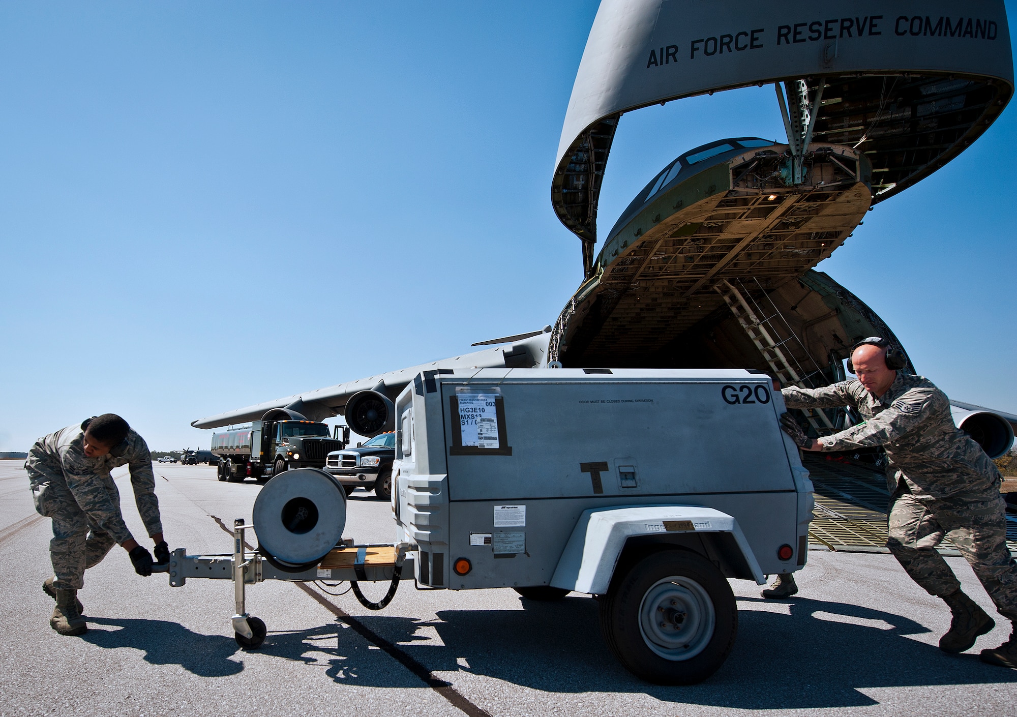 Airman 1st Class Jamal Johnson and Staff Sgt. Grant Gammons, of the 96th Logistics Readiness Squadron, move a piece of equipment away from a C-5 Galaxy March 14 at Eglin Air Force Base, Fla.  The Airmen unloaded approximately 103,165 pounds of maintenance equipment for an F-16 unit participating in a weapons system evaluation program the following week.  (U.S. Air Force photo/Samuel King Jr.)