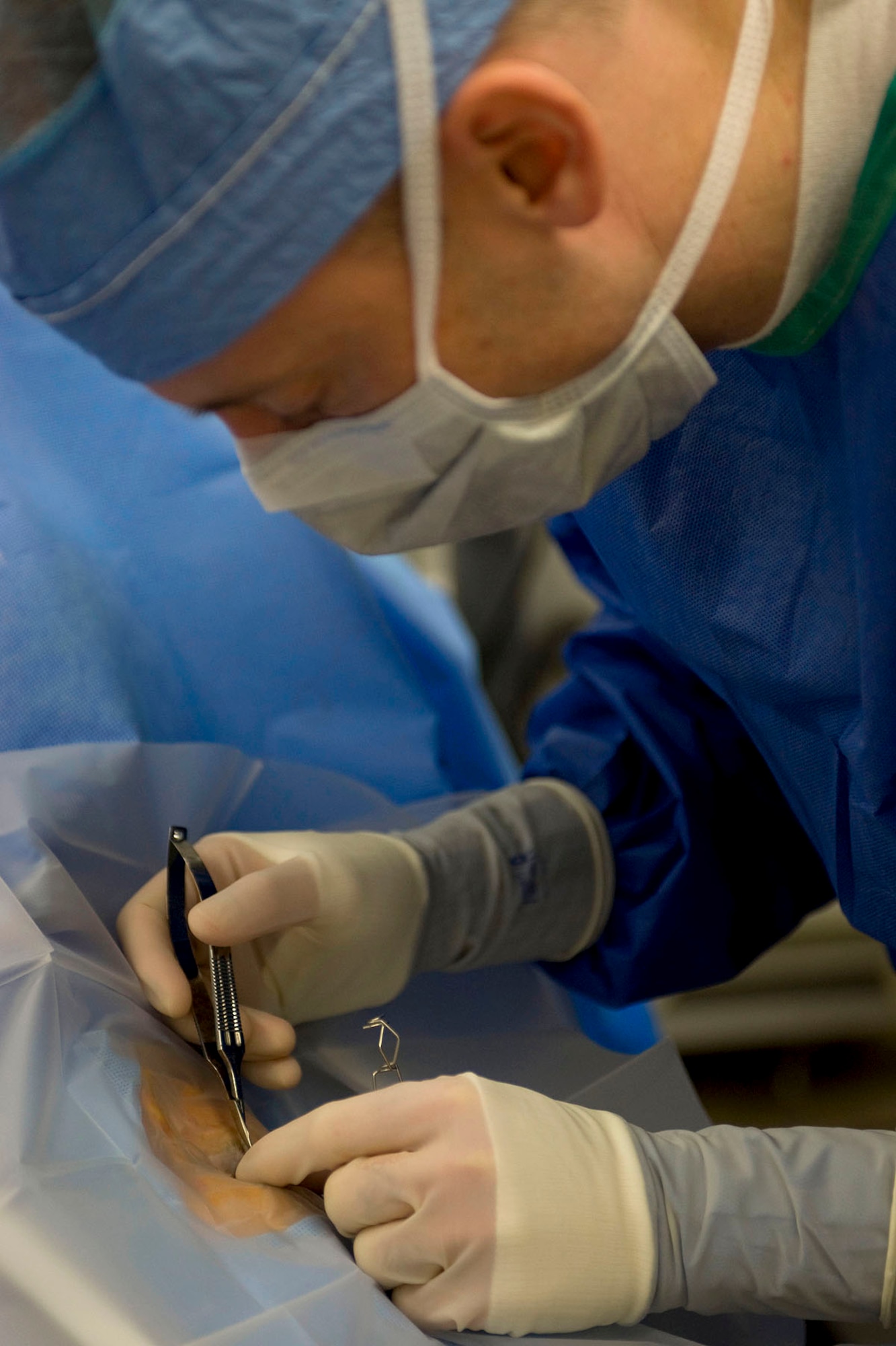 U.S. Army Dr. (Lt. Col.) Michael Hamilton, McDonald Army Health Center ophthalmologist, creates a hole through plastic covering before surgery at Fort Eustis, Va., March 7, 2013. As the sole ophthalmologist in the hospital, Hamilton is only able to conduct eye surgeries one day per week. (U.S. Air Force photo by Staff Sgt. Ashley Hawkins/Released) 