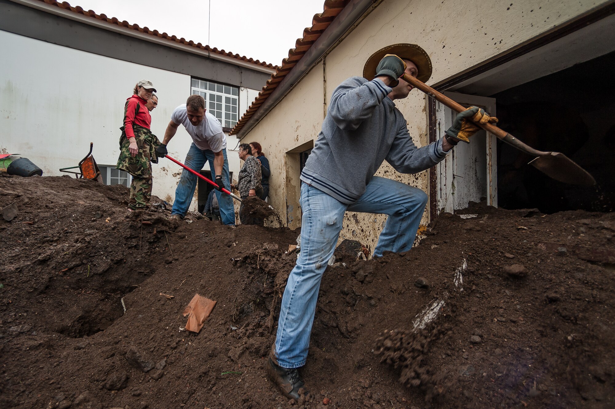 Master Sgt. Kevin Cozad (Right) along with Tech. Sgt. Dustin Guiducci both
members of the 65th Operations Support Squadron remove dirt and mud following a flood in Porto Judeu. Airmen from the 65th Operations Support Squadron and other units from Lajes Field volunteered to remove water and mud from homes and businesses following severe rain and flooding in Porto Judeu, Azores, Mar. 15, 2013. Roughly 30 homes were damaged from the flooding.  (Photo by Lucas Silva)
