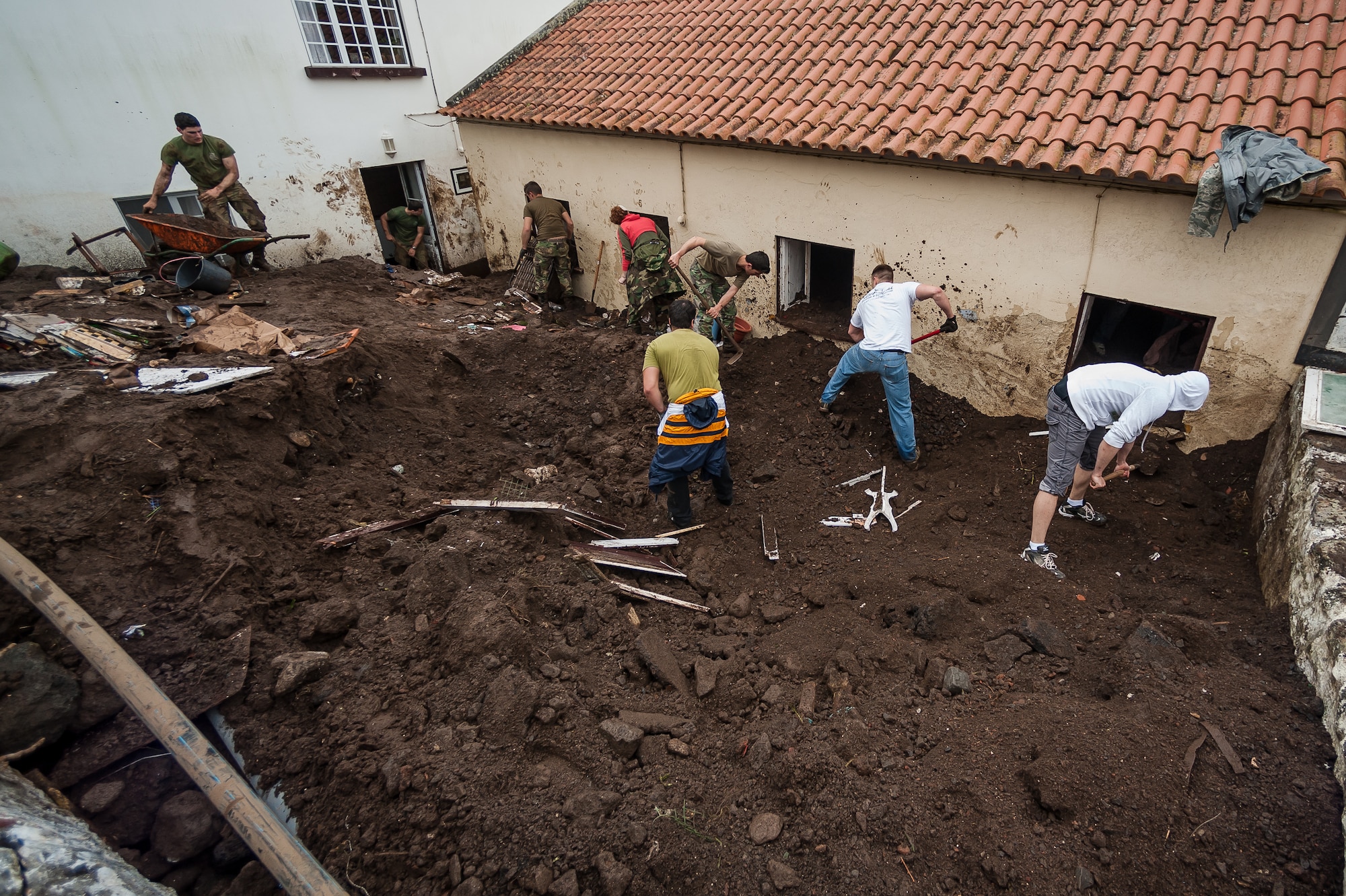 Members of 65th Operations Support Squadron along with Portuguese Army
members of Regimento de Guarnição Nº 1, remove dirt and rocks following a flood in Porto Judeu. Airmen from the 65th Operations Support Squadron and other units from Lajes Field volunteered to remove water and mud from homes and businesses following severe rain and flooding in Porto Judeu, Azores, Mar. 15, 2013. Roughly 30 homes were damaged from the flooding.  (Photo by Lucas Silva)
