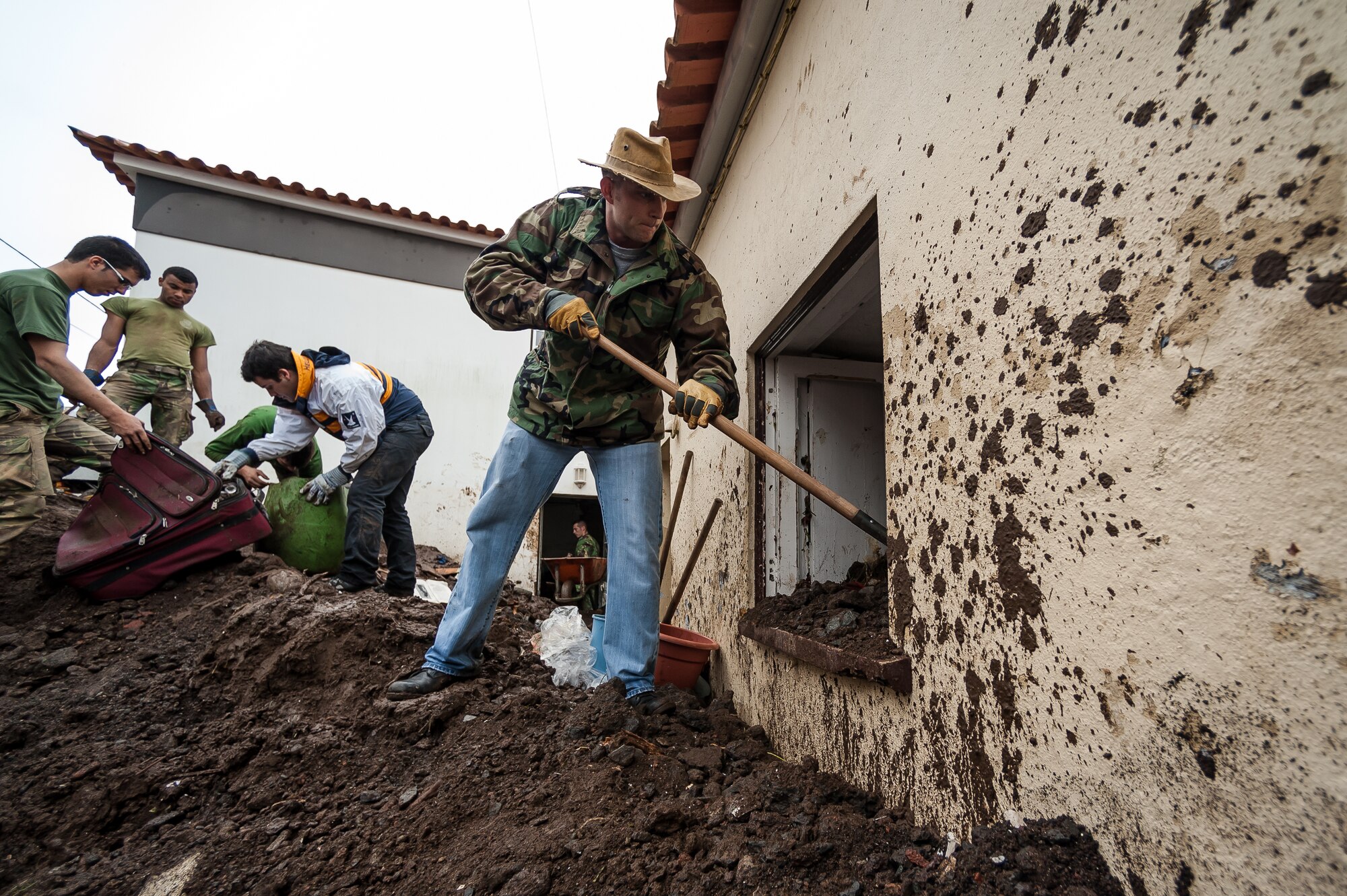 Master Sgt. Kevin Cozad, 65th Operation Support Squadron Chief Controller shovels dirt and rocks from a house In Porto Judeu that was submerged in water and mud. Airmen from the 65th Operations Support Squadron and other units from Lajes Field volunteered to remove water and mud from homes and businesses following severe rain and flooding in Porto Judeu, Azores, Mar. 15, 2013. Roughly 30 homes were damaged from the flooding.  (Photo by Lucas Silva)
