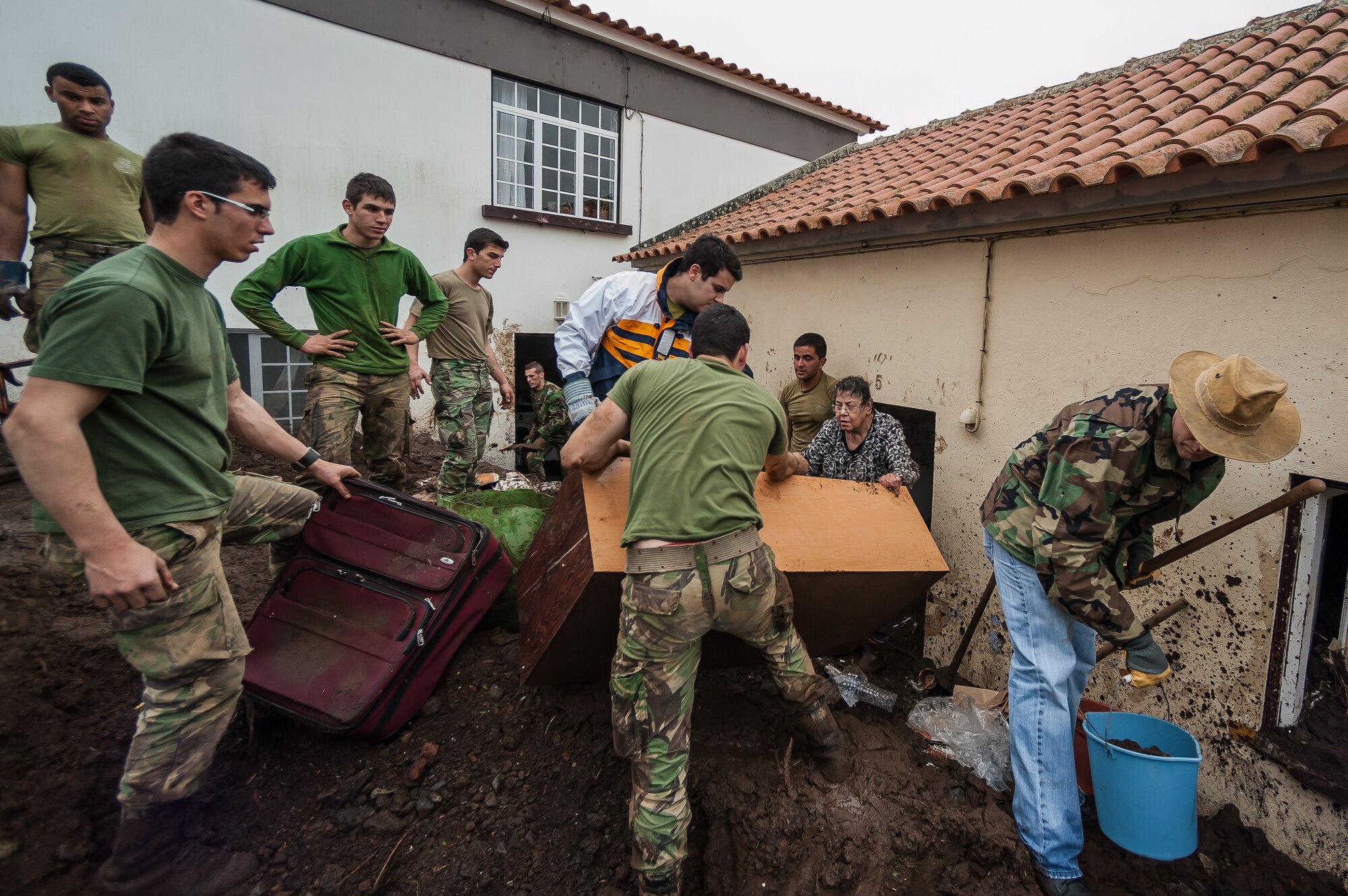 Members of 65th Operations Support Squadron along with Portuguese Army members from Regimento de Guarnição Nº 1, assist Maria de Lurdes sort through salvageable items from her house. Airmen from the 65th Operations Support Squadron and other units from Lajes Field volunteered to remove water and mud from homes and businesses following severe rain and flooding in Porto Judeu, Azores, Mar. 15, 2013. Roughly 30 homes were damaged from the flooding.  (Photo by Lucas Silva)