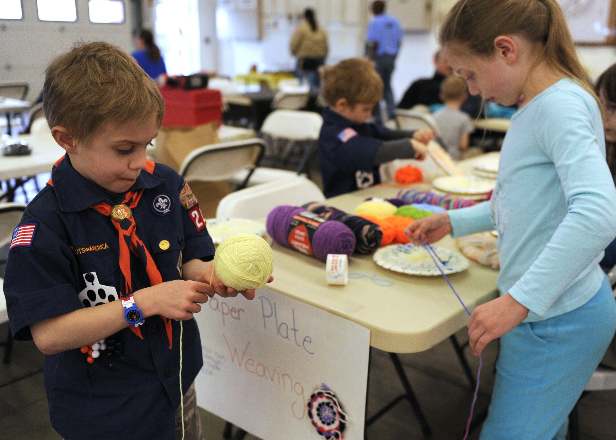 From left, Julian Isreal from Cub Scout Pack 221 from RAF Croughton, 6, and Ryann Isreal, 8, make paper-plate-weaving creations just prior to the main racing event March 16, 2013, at the Cub Scout Pinewood Derby event held in the 100th Civil Engineering Squadron Fire Department at RAF Mildenhall, England. The Boy Scouts is a club which boasts a family atmosphere where entire families, not just members, are encouraged to attend and participate. Children also made stop signs, played on a fire truck bouncy slide and had their faces painted. (U.S. Air Force photo by Tech. Sgt. Stacia Zachary/Released)