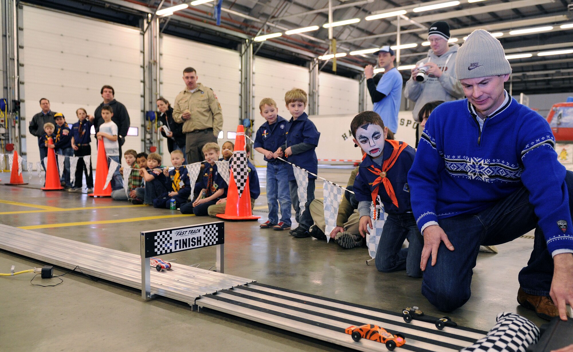 Cub Scouts and family members cheer on the racing cars March 16, 2013, during the Cub Scout Pinewood Derby event held in the 100th Civil Engineering Squadron Fire Department at RAF Mildenhall, England.  The cars are made out of pine wood. This year's car models ranged from Lego creations to the traditional pinewood blocks or balsa wood and wheels. Although the original track from 1953 was only 31 feet long, the current track is 125 feet long with electronically released gates. (U.S. Air Force photo by Tech. Sgt. Stacia Zachary/Released)