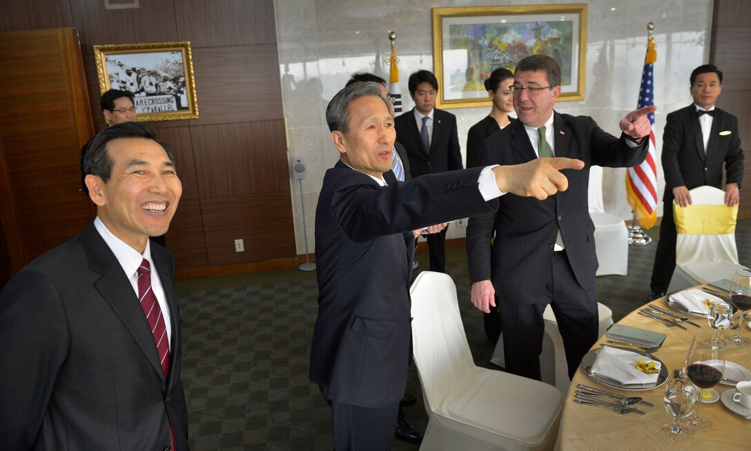 South Korean Deputy Minister Lim Kwan-bin, left, and South Korean Defense Minister Kim Kwan-jin, center, point to the view from large windows to U.S. Deputy Defense Secretary Ash Carter, right, as they prepare to sit down for a working lunch in Seoul, South Korea, March 18, 2013. 