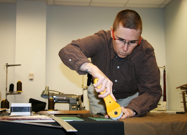 Christine Weber, a Marine Expeditionary Rifle Squad integration specialist, cuts fabric by hand in the human factors lab at the Gruntworks Squad Integration Facility. Gruntworks moved into a facility on Marine Corps Base Quantico in May 2012. It serves as a “workshop” for the MERS team to test existing and emerging equipment to help MCSC provide improved items to infantry Marines.