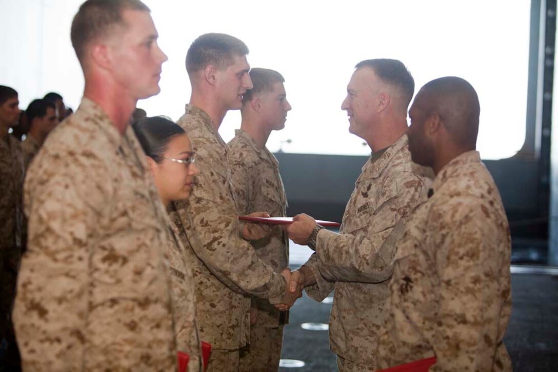 Newly promoted Cpl. Joseph Hicks, field wireman, Command Element, 15th Marine Expeditionary Unit, shakes hands with Col. Scott D. Campbell, his commanding officer, in the hangar bay of USS Peleliu, March 1. The 15th MEU is deployed as part of the Peleliu Amphibious Ready Group as a U.S. Central Command theater reserve force, providing support for maritime security operations and theater security cooperation efforts in the U.S. 5th Fleet area of responsibility. (U.S. Marine Corps photo by Cpl. Danny L. Shaffer)