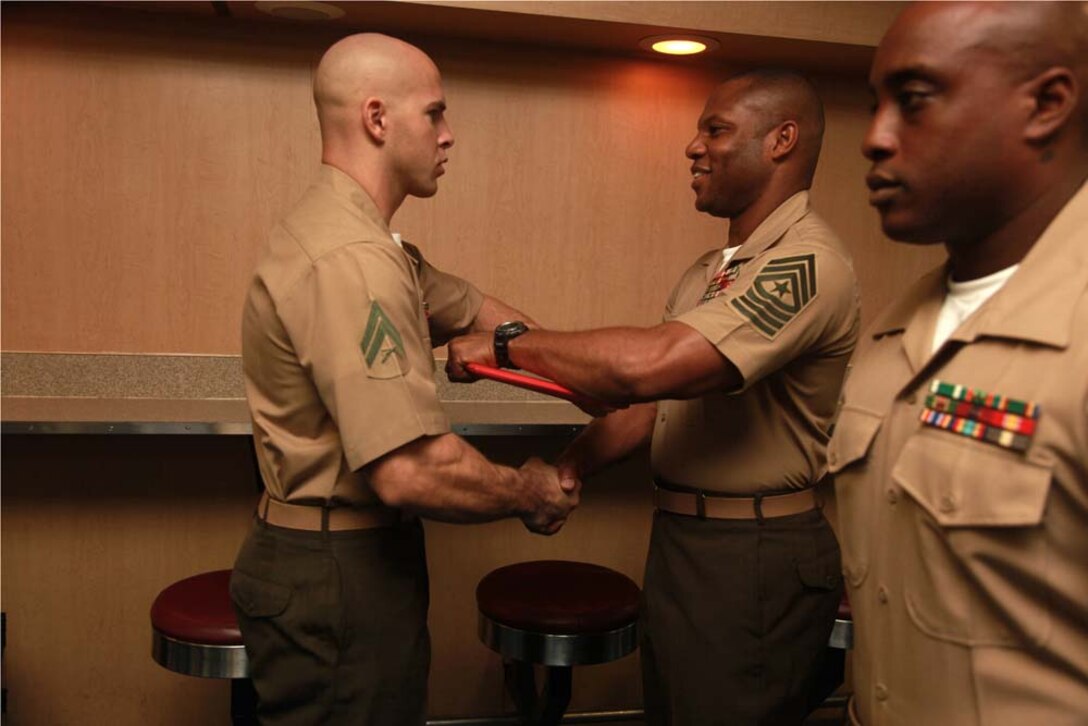 Corporal Joseph P. Davis, machinegun squad leader, Weapons Platoon, Kilo Company, Battalion Landing Team 3/5, 15th Marine Expeditionary Unit, receives his graduation certificate from Sgt. Maj. John W. Scott, the 15th MEU's sergeant major, on the troop mess decks of USS Peleliu during Corporals' Course graduation, March 15. Corporals' Course is a professional military education for enlisted Marines designed to give corporals the tools to become more effective small unit leaders. The 15th MEU is deployed as part of the Peleliu Amphibious Ready Group as a U.S. Central Command theater reserve force, providing support for maritime security operations and theater security cooperation efforts in the U.S. 5th Fleet area of responsibility. Davis, 24, is from Wichita Falls, Texas. (U.S. Marine Corps photo by Cpl. John Robbart III)