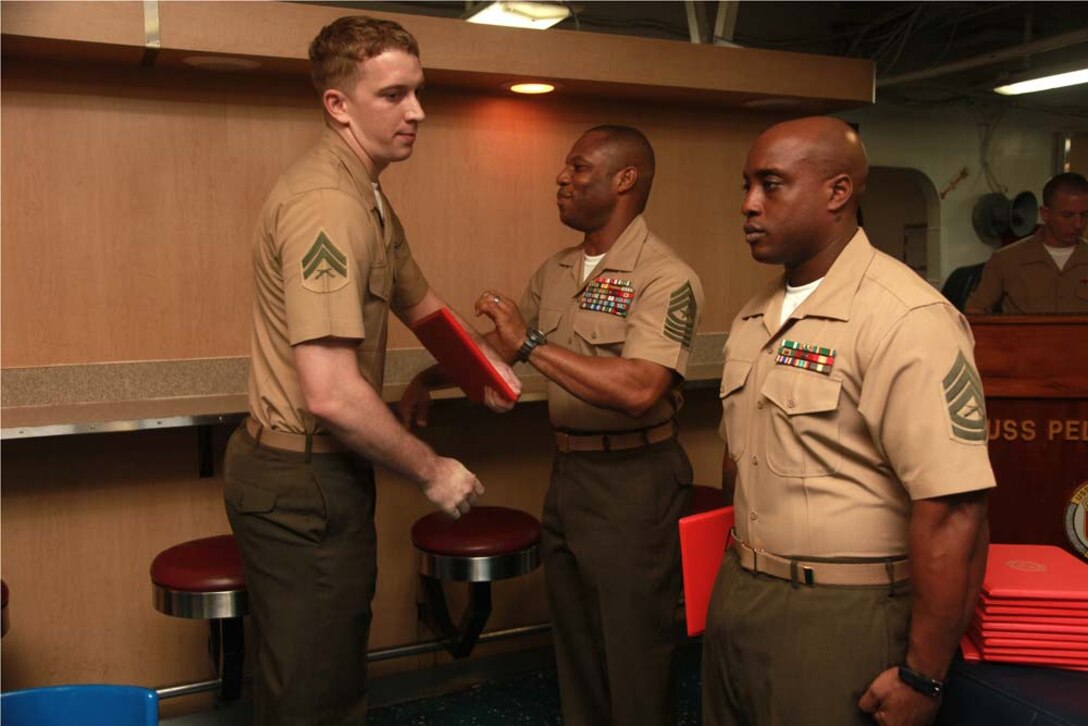 Corporal Brandon C. Houser, radio technician, Command Element, 15th Marine Expeditionary Unit, receives his graduation certificate from Sgt. Maj. John W. Scott, the 15th MEU sergeant major, on the troop mess decks of USS Peleliu during Corporals' Course graduation, March 15. Corporals' Course is a professional military education for enlisted Marines designed to give corporals the tools to become more effective small unit leaders. The 15th MEU is deployed as part of the Peleliu Amphibious Ready Group as a U.S. Central Command theater reserve force, providing support for maritime security operations and theater security cooperation efforts in the U.S. 5th Fleet area of responsibility. Houser, 22, is from Paradise, Calif. (U.S. Marine Corps photo by Cpl. John Robbart III)