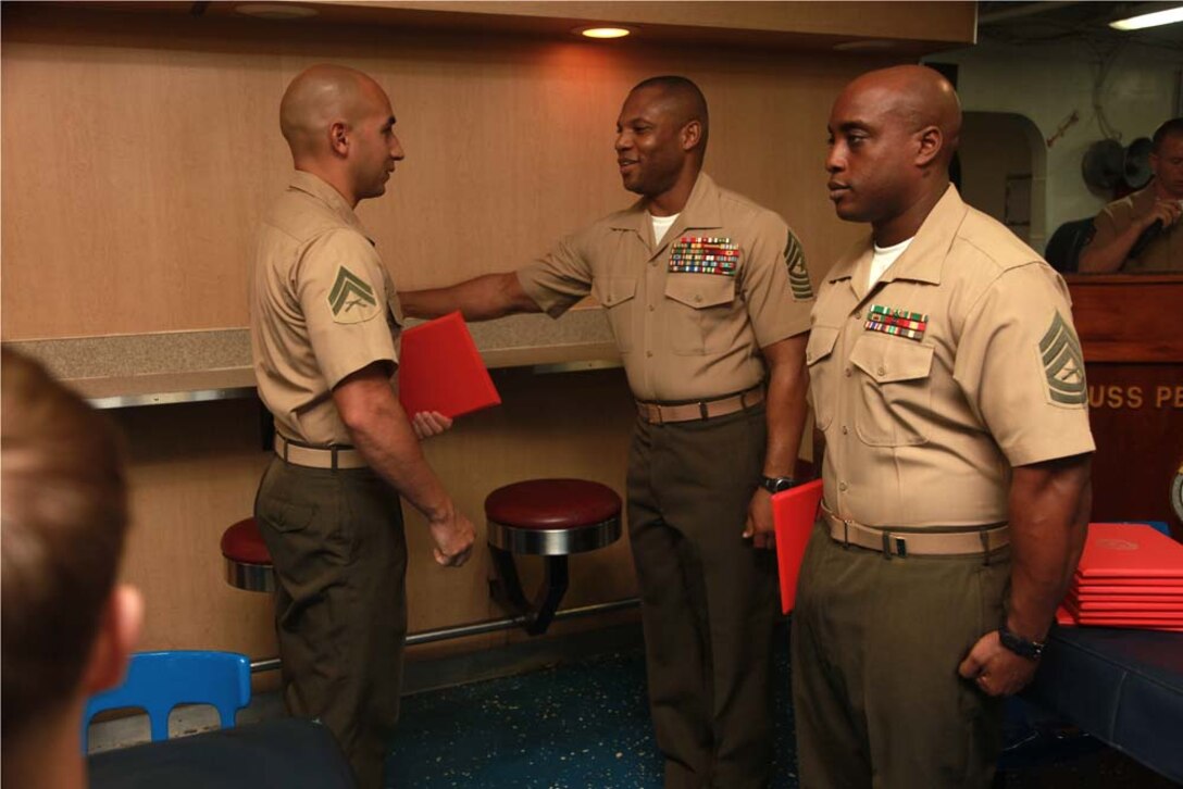 Corporal Jeremy V. Martinez, low-altitude air-defense gunner, Marine Medium Helicopter Squadron 364 (Rein.), 15th Marine Expeditionary Unit, receives his graduation certificate from Sgt. Maj. John W. Scott, the 15th MEU sergeant major, on the troop mess decks of USS Peleliu during Corporals' Course graduation, March 15. Corporals' Course is a professional military education for enlisted Marines designed to give corporals the tools to become more effective small unit leaders. The 15th MEU is deployed as part of the Peleliu Amphibious Ready Group as a U.S. Central Command theater reserve force, providing support for maritime security operations and theater security cooperation efforts in the U.S. 5th Fleet area of responsibility. Martinez, 28, is from Garden City, Kan. (U.S. Marine Corps photo by Cpl. John Robbart III)