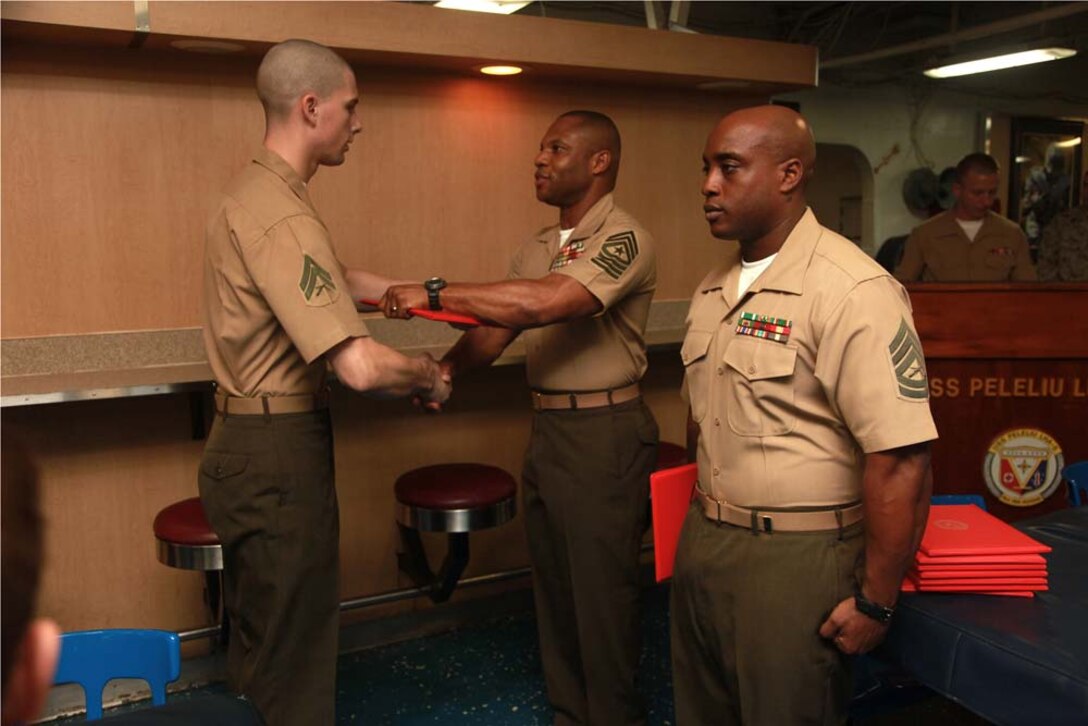 Corporal Andrew A. Perkins, food service specialist, Marine Medium Helicopter Squadron 364 (Rein.), 15th Marine Expeditionary Unit, receives his graduation certificate from Sgt. Maj. John W. Scott, the 15th MEU sergeant major, on the troop mess decks of USS Peleliu during Corporals' Course graduation, March 15. Corporals' Course is a professional military education for enlisted Marines designed to give corporals the tools to become more effective small unit leaders. The 15th MEU is deployed as part of the Peleliu Amphibious Ready Group as a U.S. Central Command theater reserve force, providing support for maritime security operations and theater security cooperation efforts in the U.S. 5th Fleet area of responsibility. Perkins, 21, is from Laconia, N.H. (U.S. Marine Corps photo by Cpl. John Robbart III)