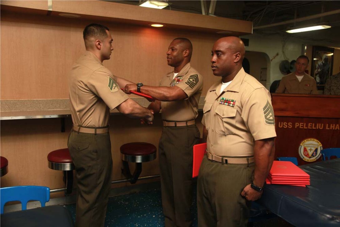 Corporal Armando Ramirez, individual material readiness list asset manager, Marine Medium Helicopter Squadron 364 (Rein.), 15th Marine Expeditionary Unit, receives his graduation certificate from Sgt. Maj. John W. Scott, the 15th MEU sergeant major, on the troop mess decks of USS Peleliu during Corporals' Course graduation, March 15. Corporals' Course is a professional military education for enlisted Marines designed to give corporals the tools to become more effective small unit leaders. The 15th MEU is deployed as part of the Peleliu Amphibious Ready Group as a U.S. Central Command theater reserve force, providing support for maritime security operations and theater security cooperation efforts in the U.S. 5th Fleet area of responsibility. Ramirez, 23, is from Laredo, Texas. (U.S. Marine Corps photo by Cpl. John Robbart III)